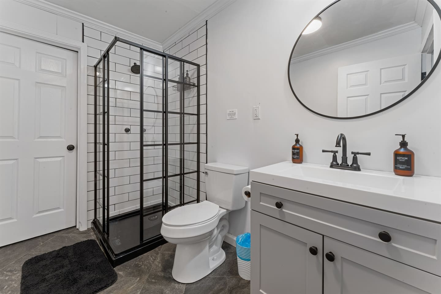 Modern, spotless bathroom featuring a stylish black-framed walk-in shower, spacious vanity, and all essentials provided for a comfortable stay.