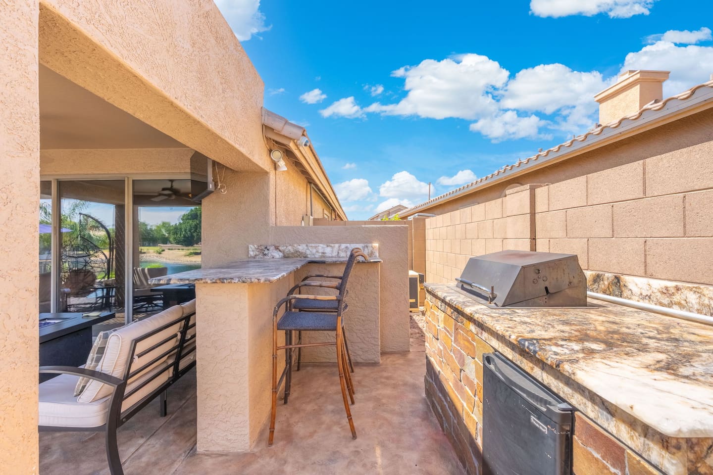 The fully equipped outdoor kitchen makes entertaining effortless — a built-in grill, granite counter, bar seating, and a mini fridge mean you can cook, serve, and enjoy without ever heading inside.