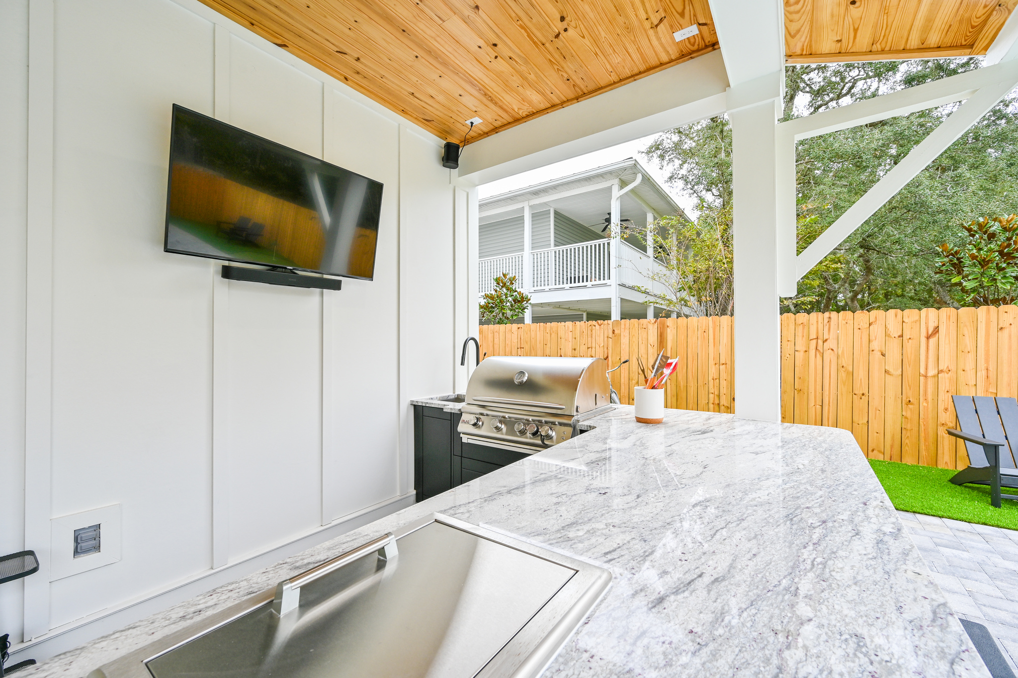 Summer Kitchen equipped with a 50" Smart TV, Surround Sound, ice box, and a Built-In Grill
