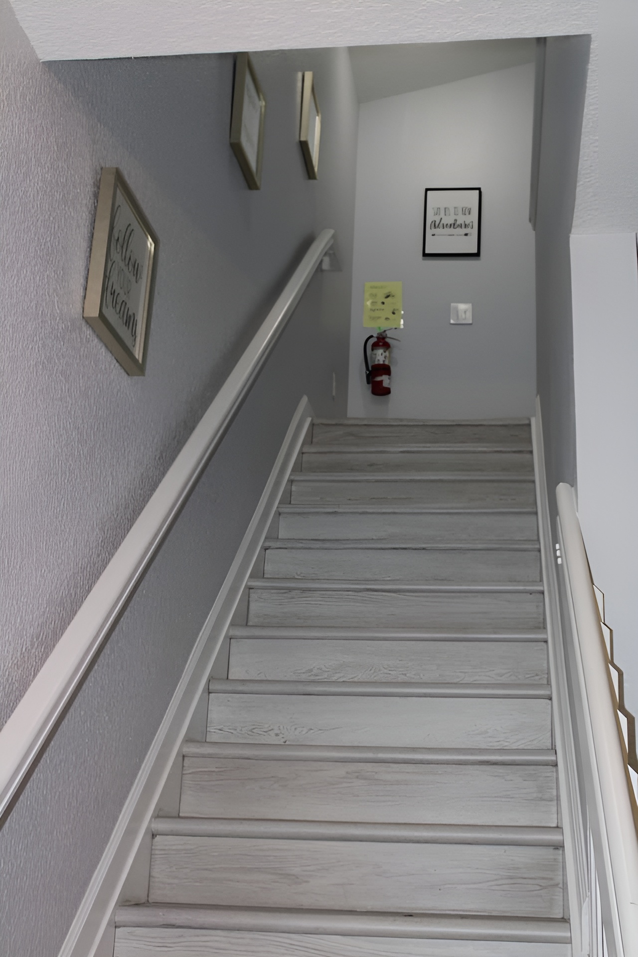 - Stairway with soft gray walls and motivational art for an inviting ascent  
- Wide steps and railing provide safety and ease for all guests  
- Leads to cozy upstairs bedrooms and additional living spaces  
