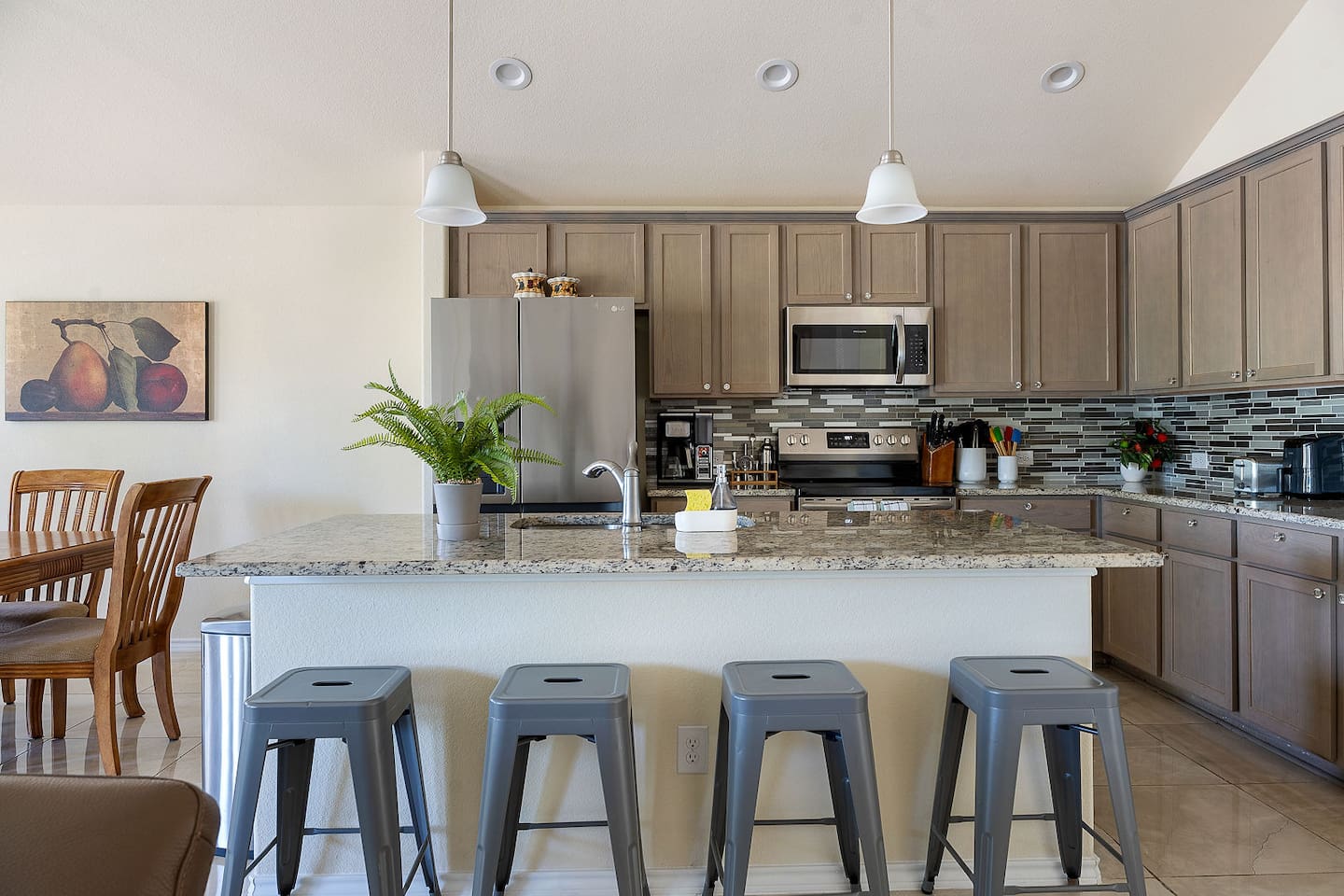 Step into a modern kitchen with stainless steel appliances, sleek cabinetry, and a spacious island with barstool seating for casual meals.