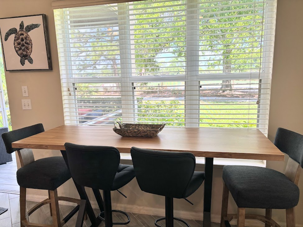 Bright dining area with a large table, modern seating, and peaceful views through the wide windows.