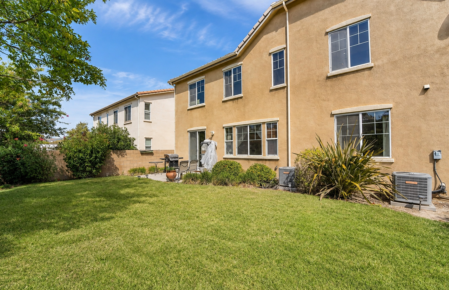 Backyard with a grassy lawn, patio seating, and plenty of space to enjoy the fresh air.