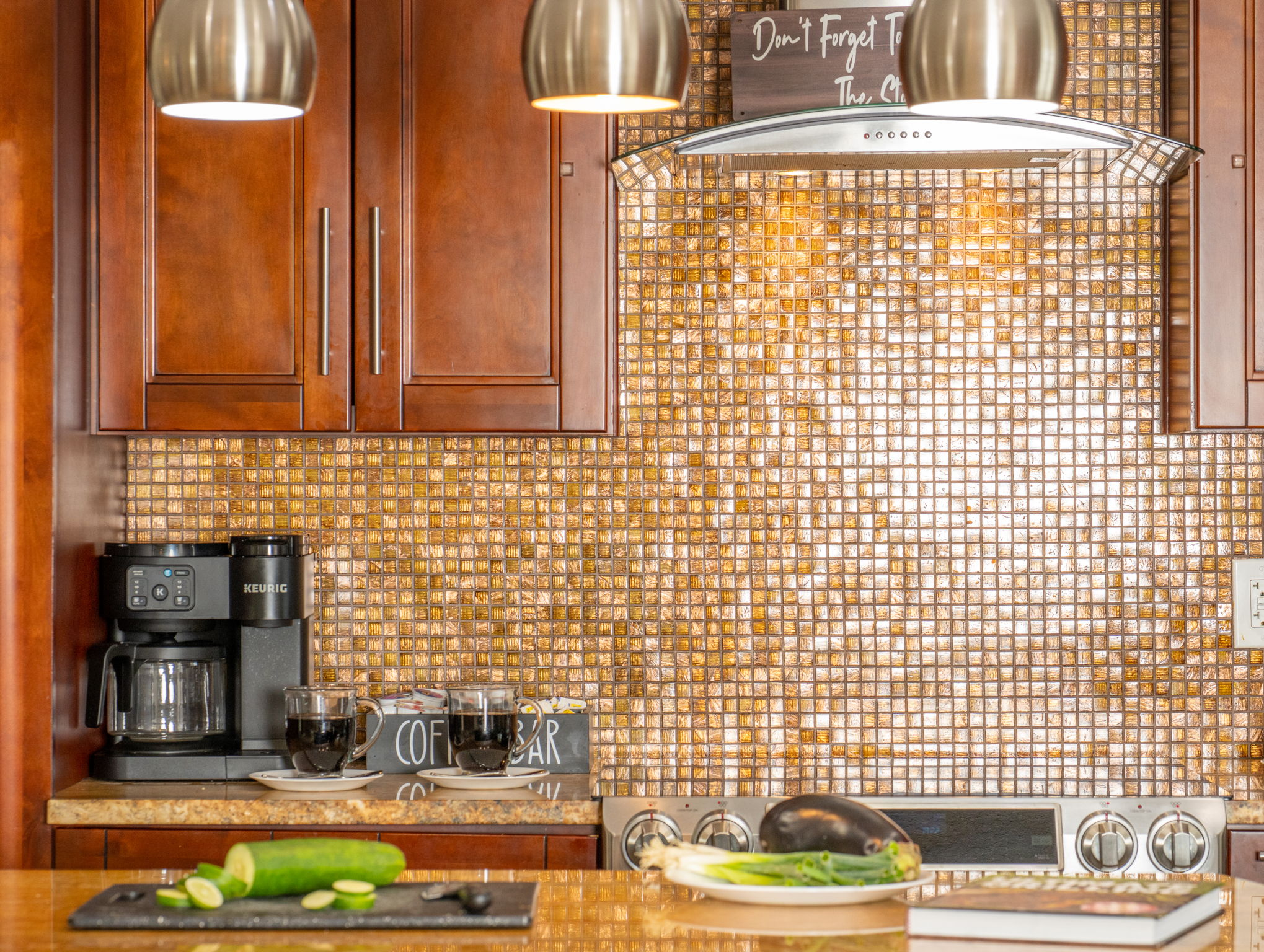 The rich wood cabinets and gold-hued surfaces pair beautifully with contemporary stainless fixtures for a balanced, stylish kitchen.
