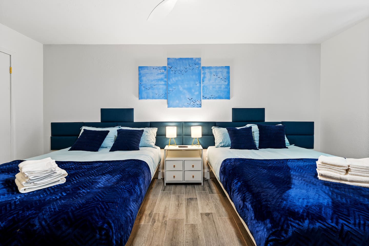 Spacious bedroom with two plush queen beds, blackout curtains, and a smart TV—ideal for families or groups to unwind in comfort.