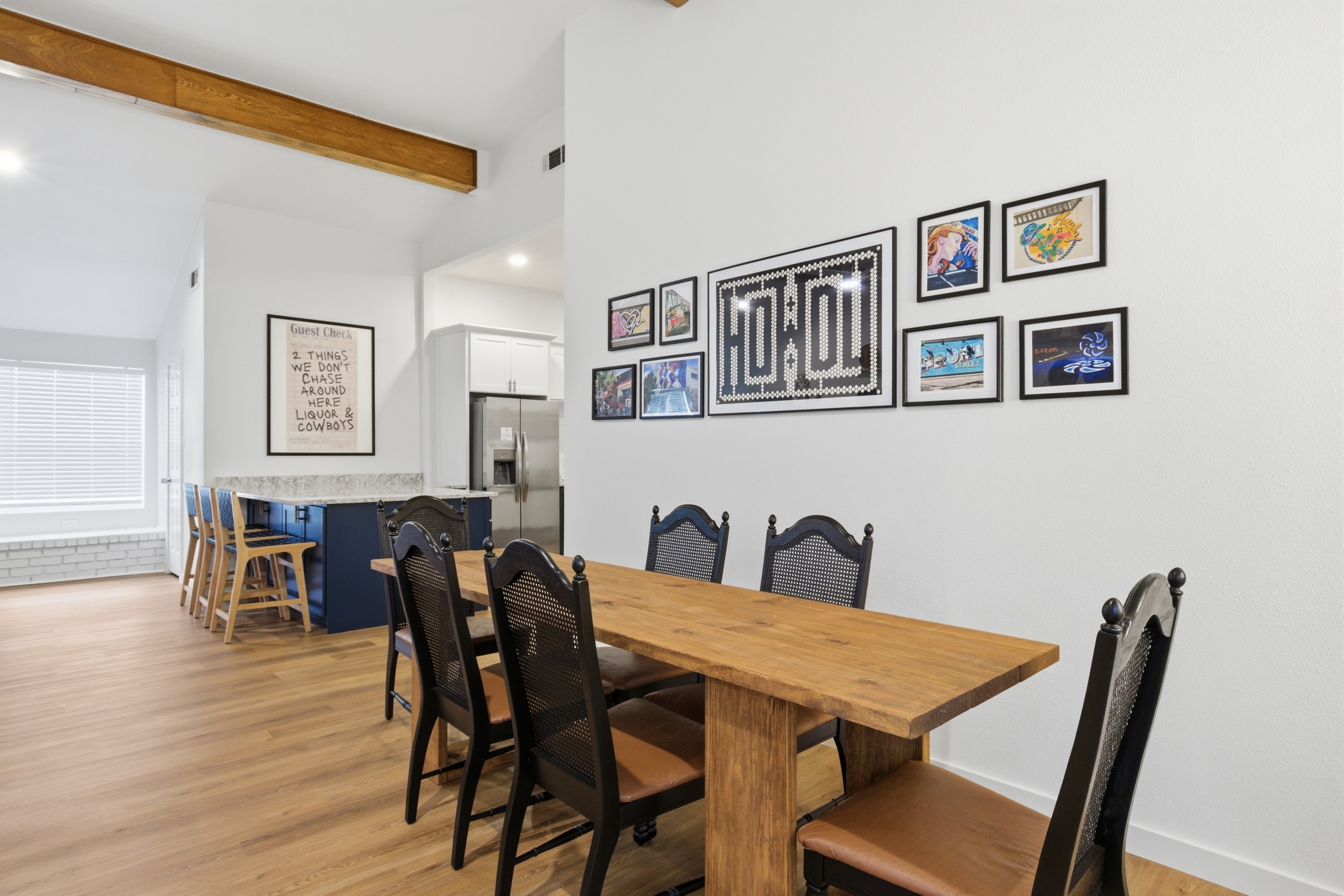 Dining table seats 8 with wood farmhouse table and black chairs. Open layout connects to fully stocked kitchen. Perfect for pregame group meals near AT&T Stadium.
