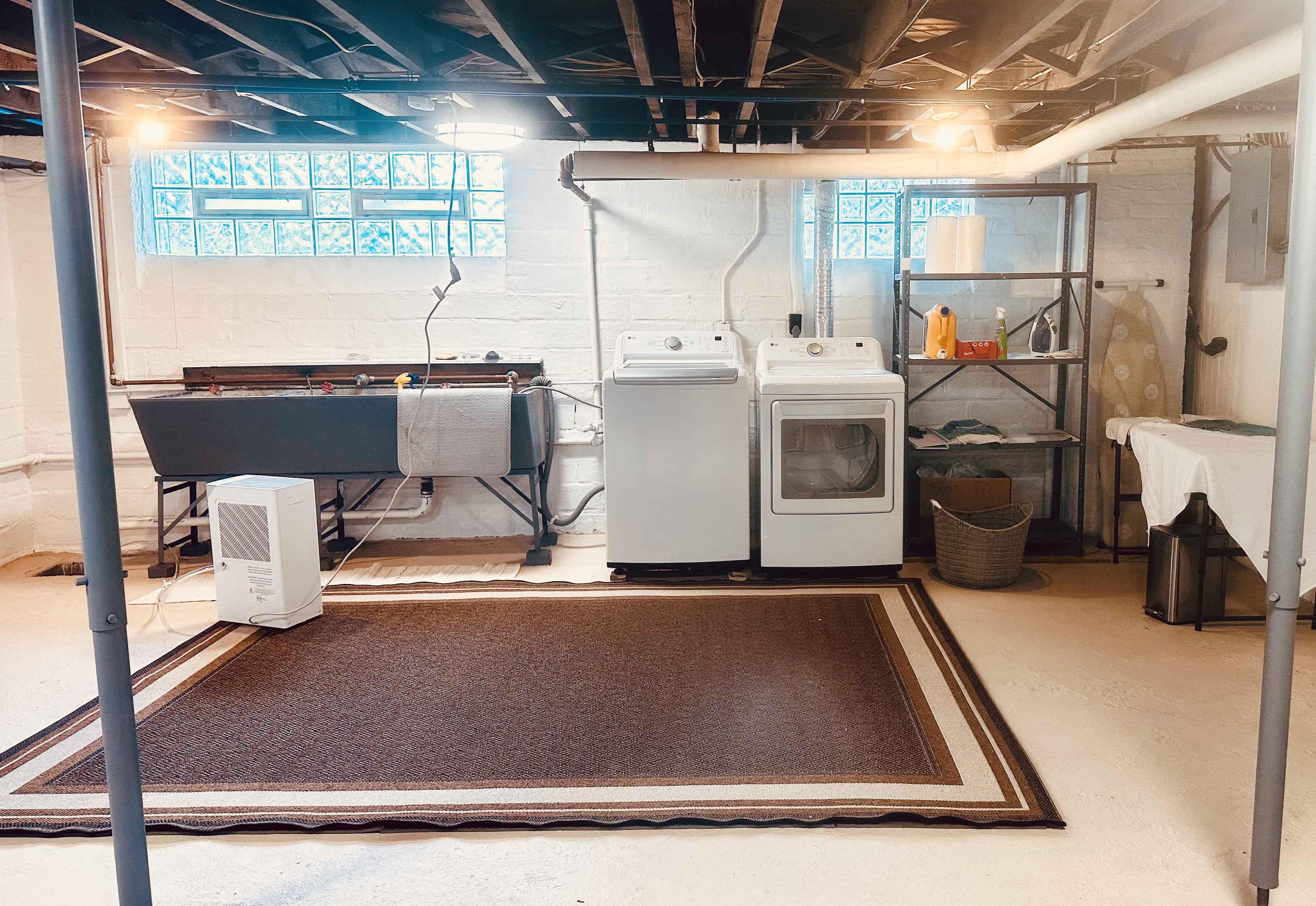 Newer washer & dryer, with three industrial utility sinks in the well lit basement.