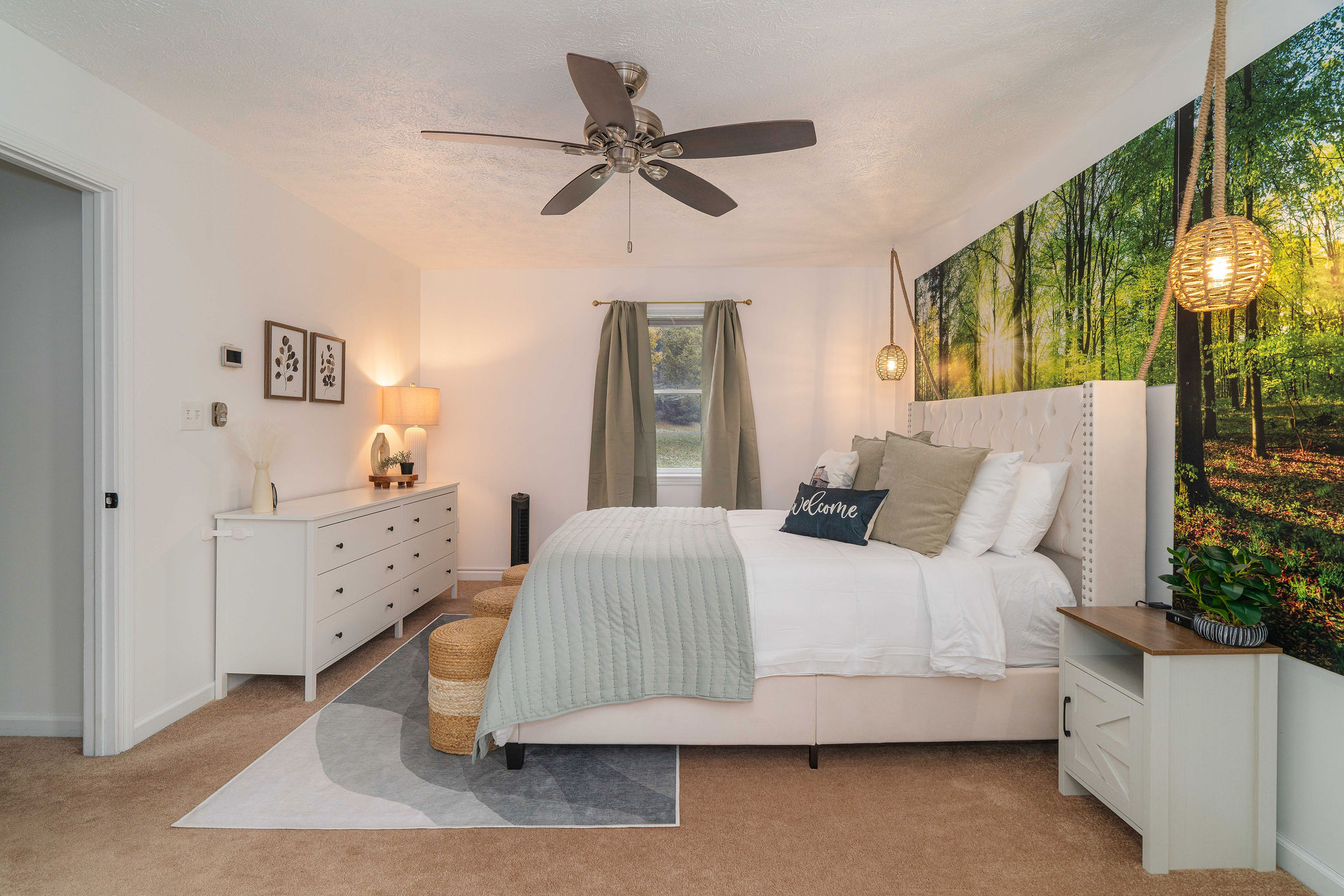 Spacious primary bedroom with Woodland Sunrise feature wall, queen bed, plush linens, and peaceful forest views.
