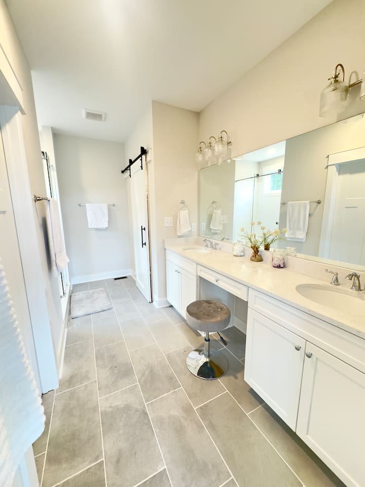 The master bath has a spa vibe with light flooding in from windows in the large glass shower. Guests will love the double quartz vanity with the seated make-up area and huge walk-in closet with barn doors. SO many curated details in the master suite!