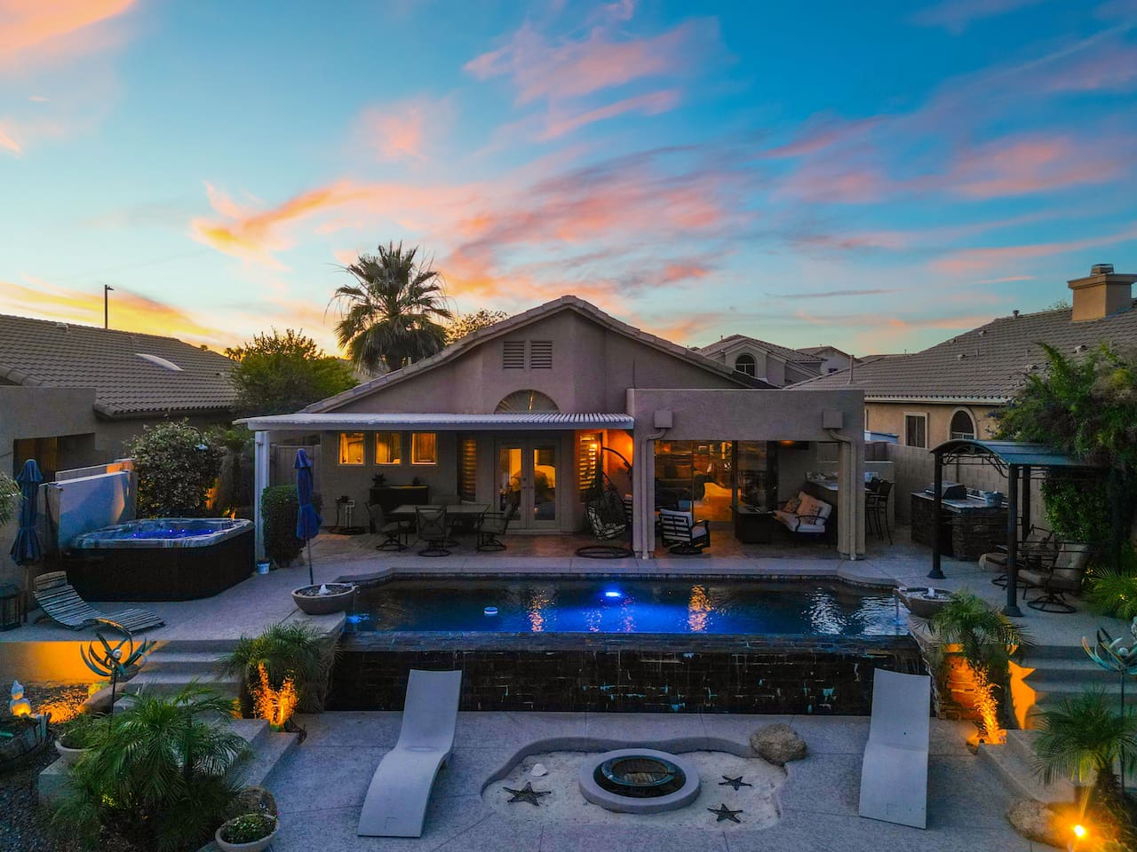 As the day fades, the backyard transforms — pool lights shimmer, landscape lighting glows, and the covered patio invites you to linger long into the warm Arizona night.