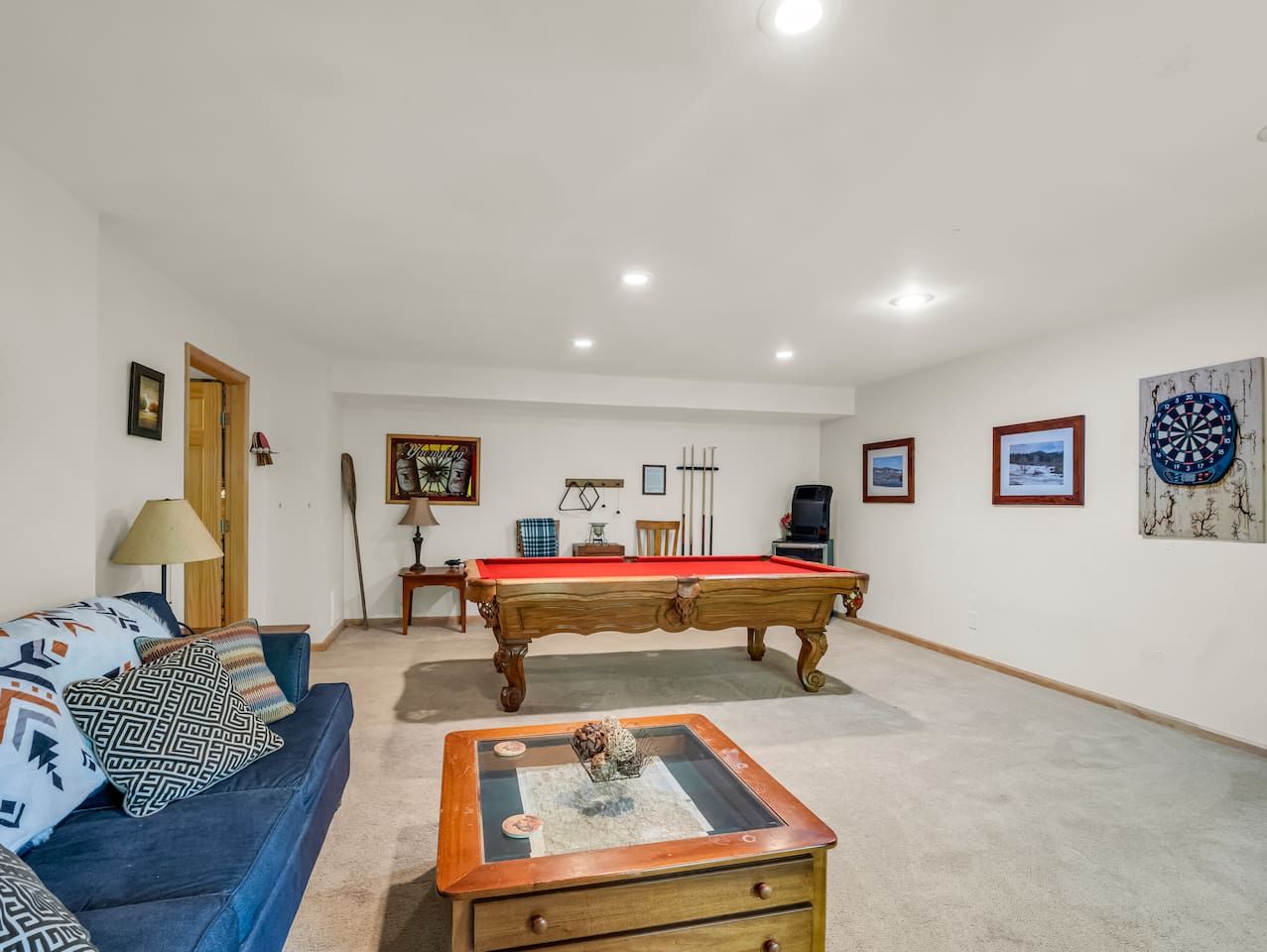 Basement with seating, pool table, dart board, variety of board games, and television