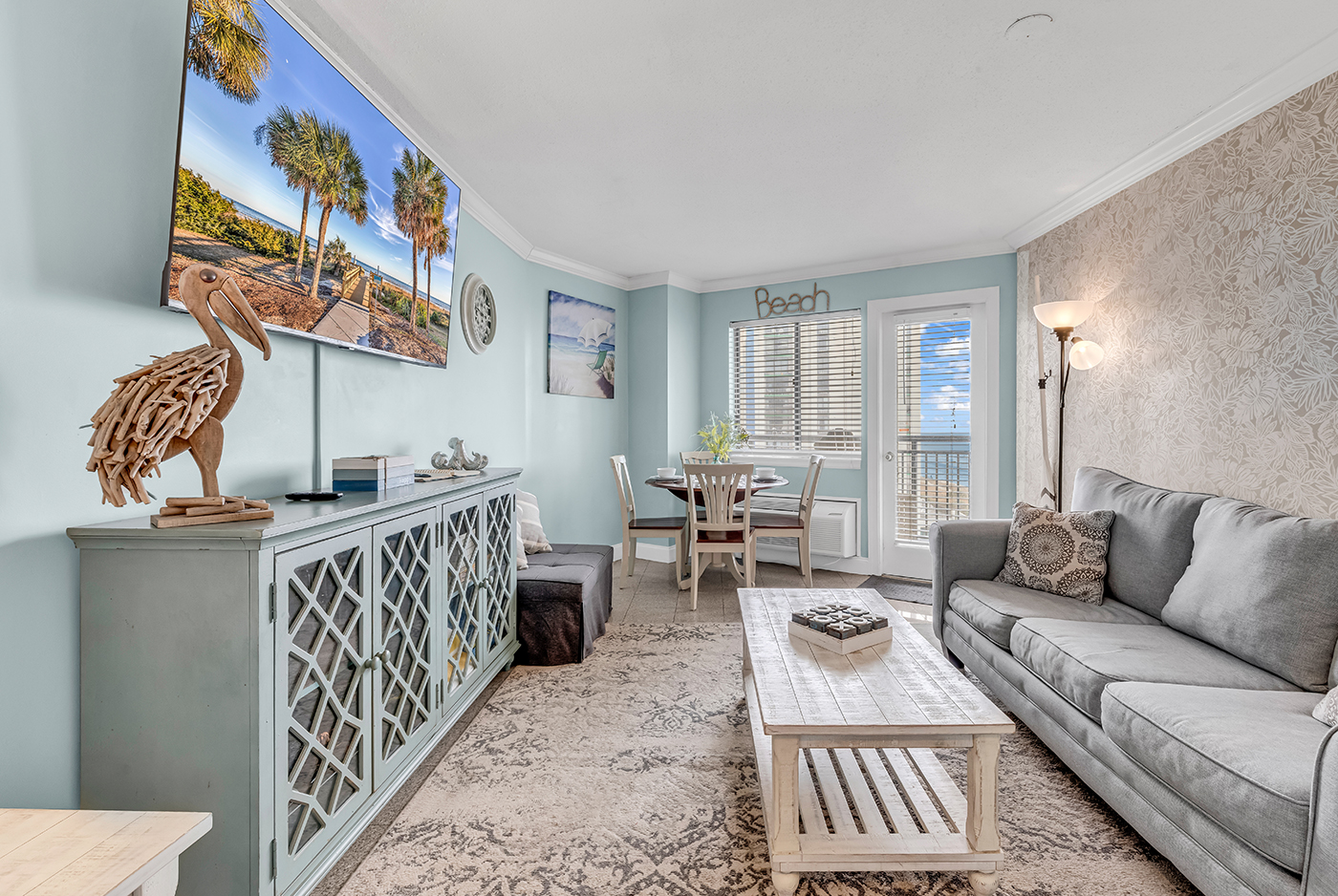 Spacious living room with 65-inch flat-screen TV, comfortable sofa, and coastal décor