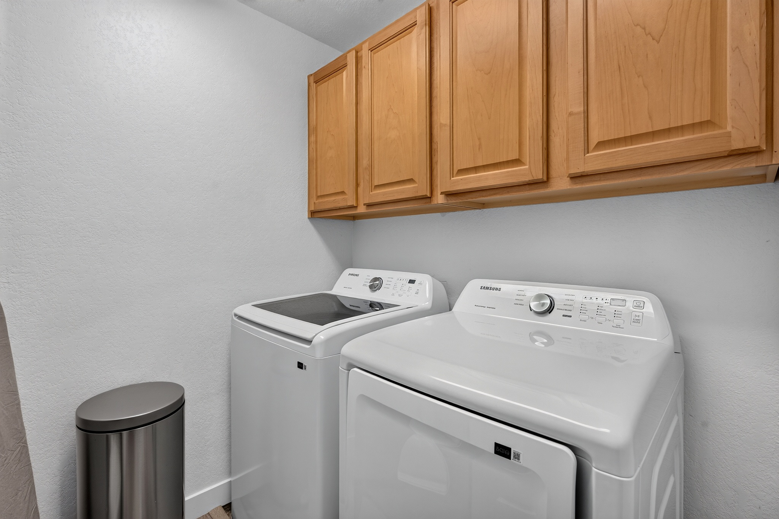 In- unit laundry area with washer, dryer, and overhead cabinet storage for added convenience during your stay.
