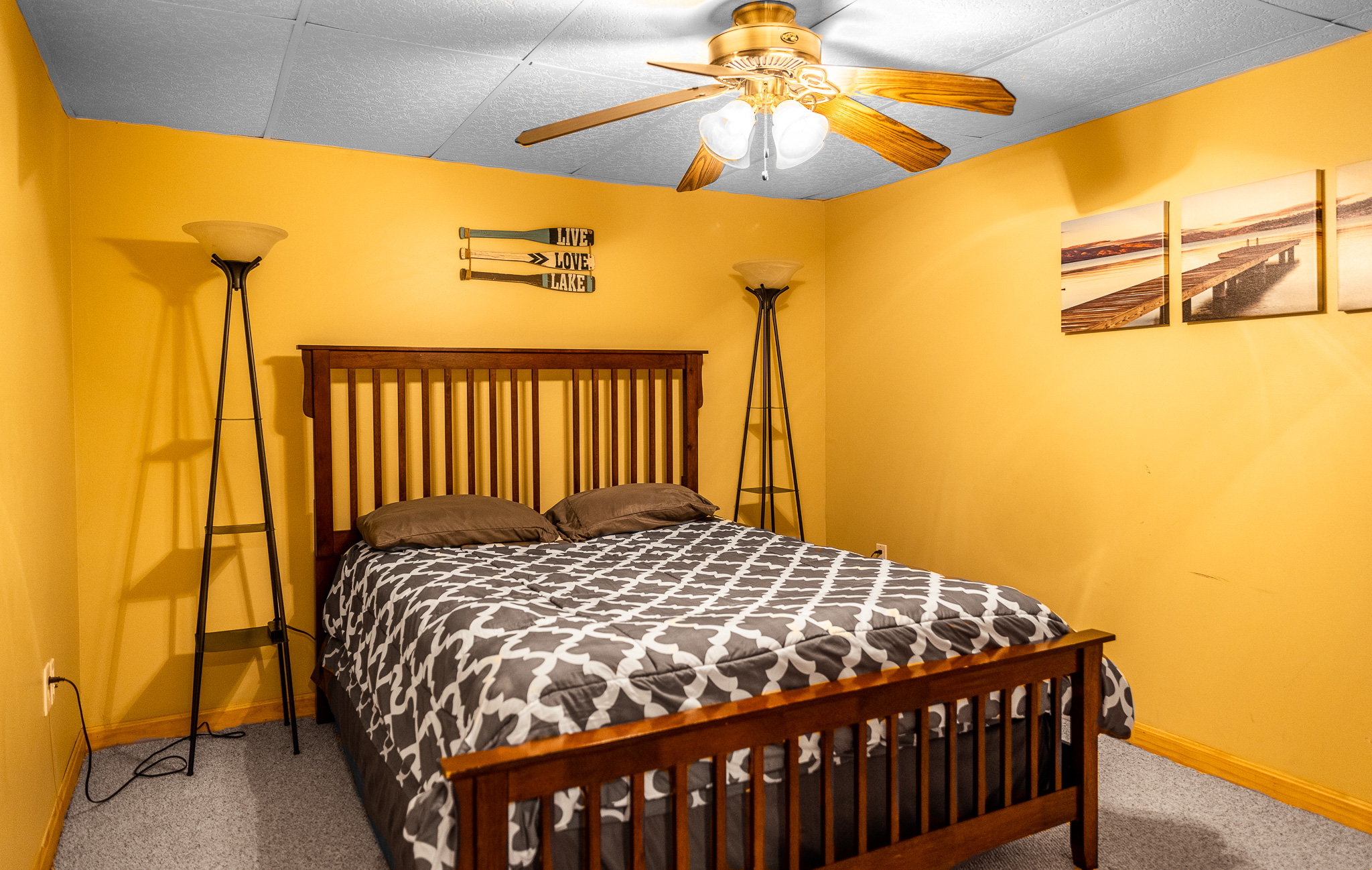 Downstairs bedroom with queen bed, closet, ceiling fan.