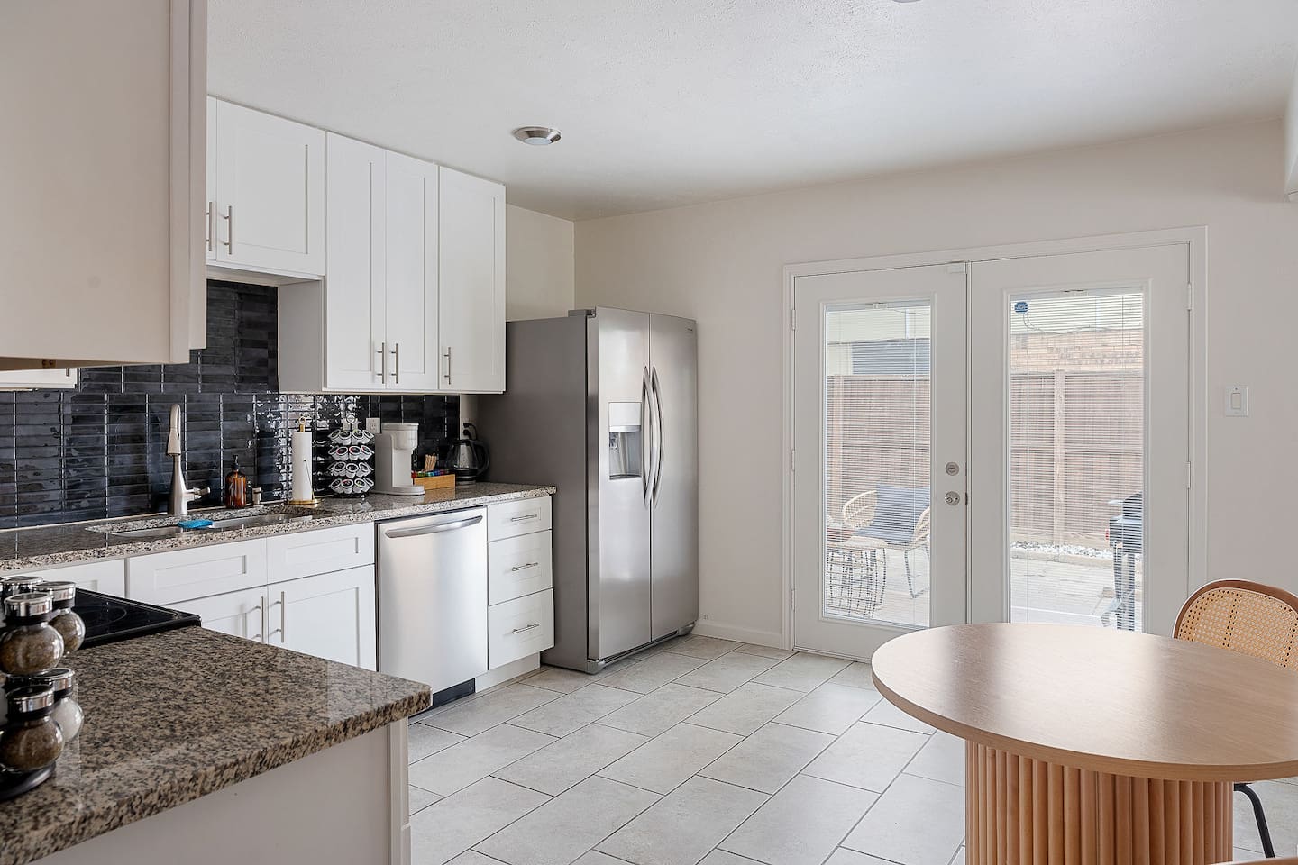 Relish in this spacious kitchen featuring modern appliances and a cozy dining area. The French doors lead to a charming outdoor patio.