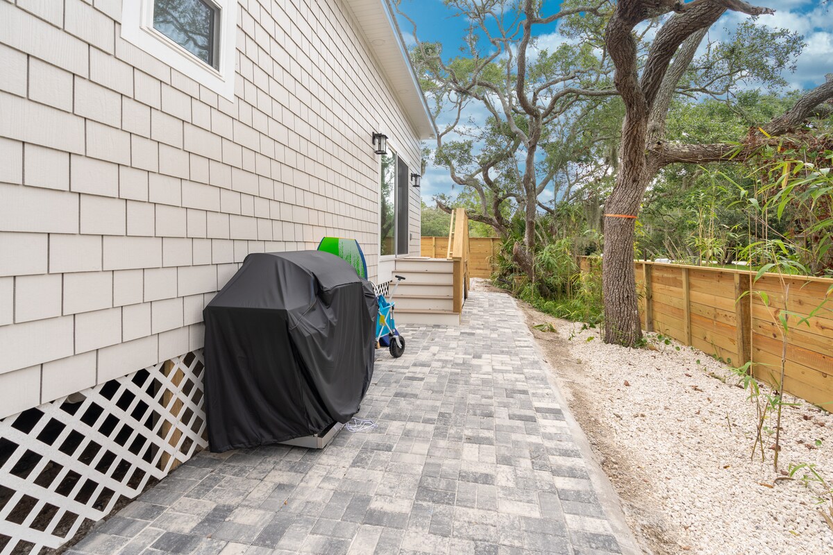 The gas grill lives along the side path, next to the beach wagon and the boogie boards. Load the cart in the morning, walk it down to the sand, and bring it back in time to put something on the grill for dinner.