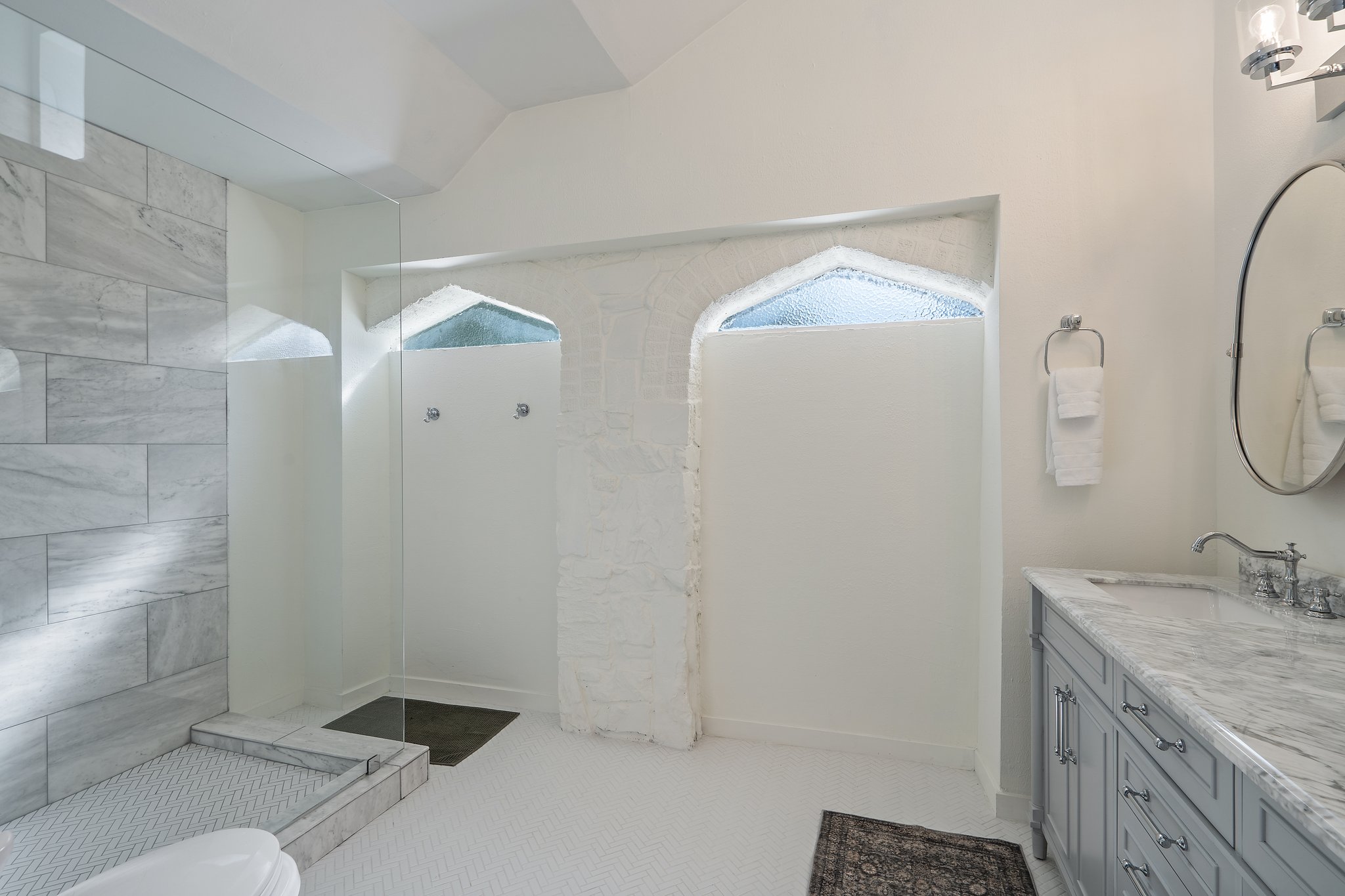 Bathroom 1 walk-in shower with floor-to-ceiling tile surround and arched ceiling detail. Stocked with Ginger Lily Farms shampoo, conditioner, and shower gel. Fresh towels, hairdryer, and essentials provided.