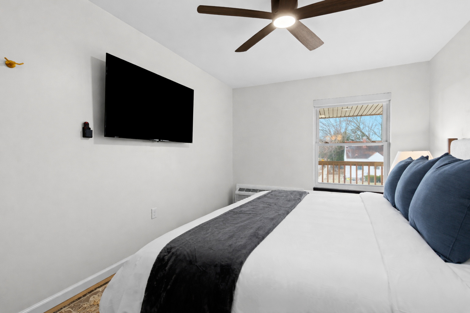 Calm, modern bedroom with a plush bed, ceiling fan, and smart TV—designed for restful nights and relaxed mornings.