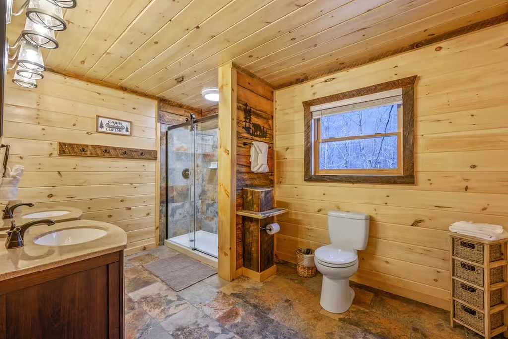 The upper level bathroom at Bear Paws Cabin features a double vanity with dual mirrors &mdash; no fighting over the sink in the morning. Bonus for families: a stacked washer and dryer is tucked right in, so you can pack lighter and do laundry mid-trip