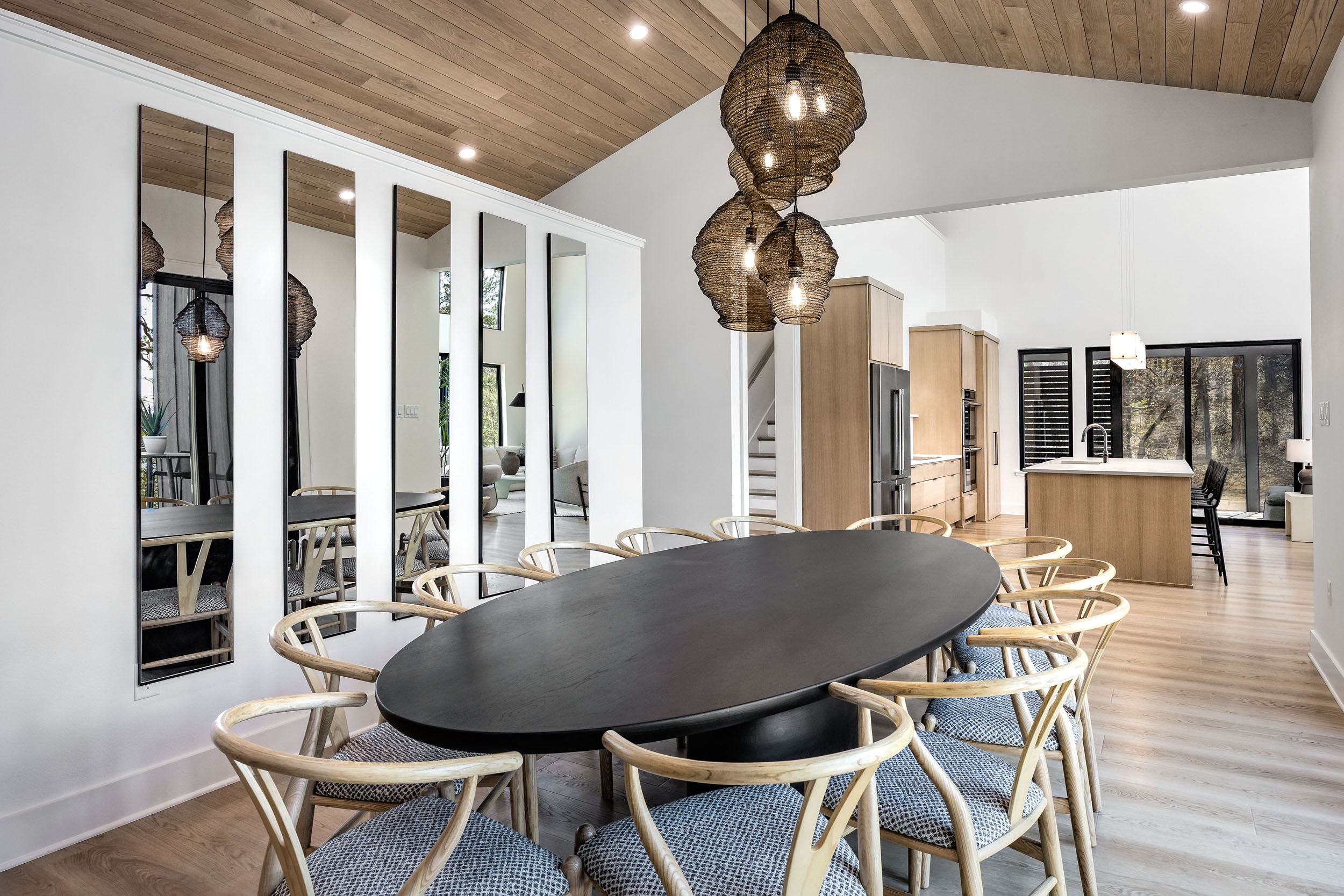 Gather your group around the large dining table with views of the outdoor deck and woods beyond—perfect for shared meals and memories.