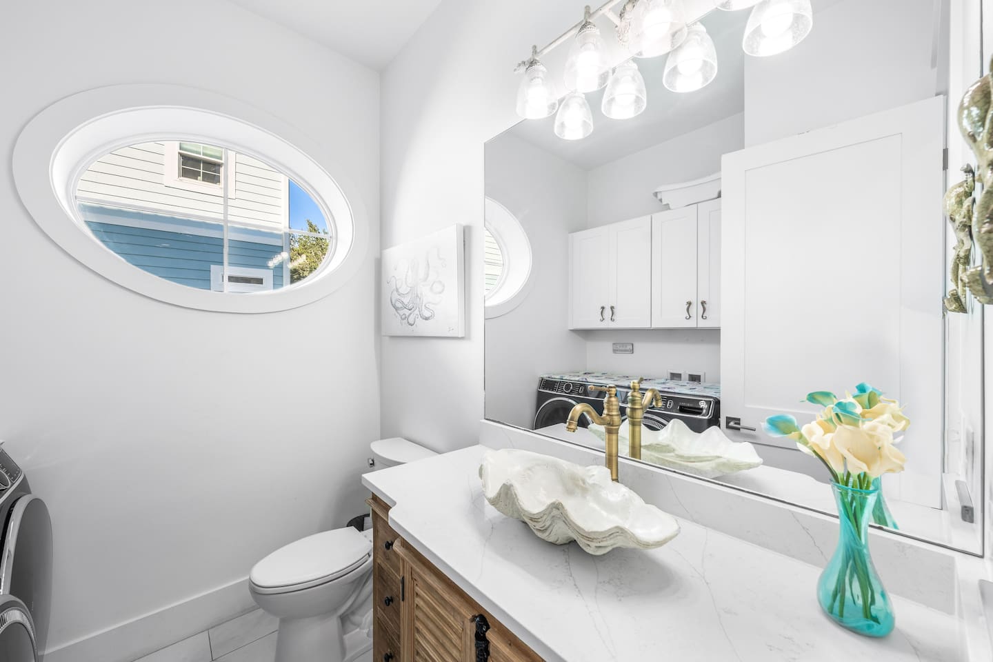 Main-floor half-bath doubles as  laundry suite!  Features a unique designer shell sink and bespoke 18th-century cabinetry and unique seahorse handles. Equipped with premium washer/dryer, iron, and beach towels—convenience meets 30A coastal style.