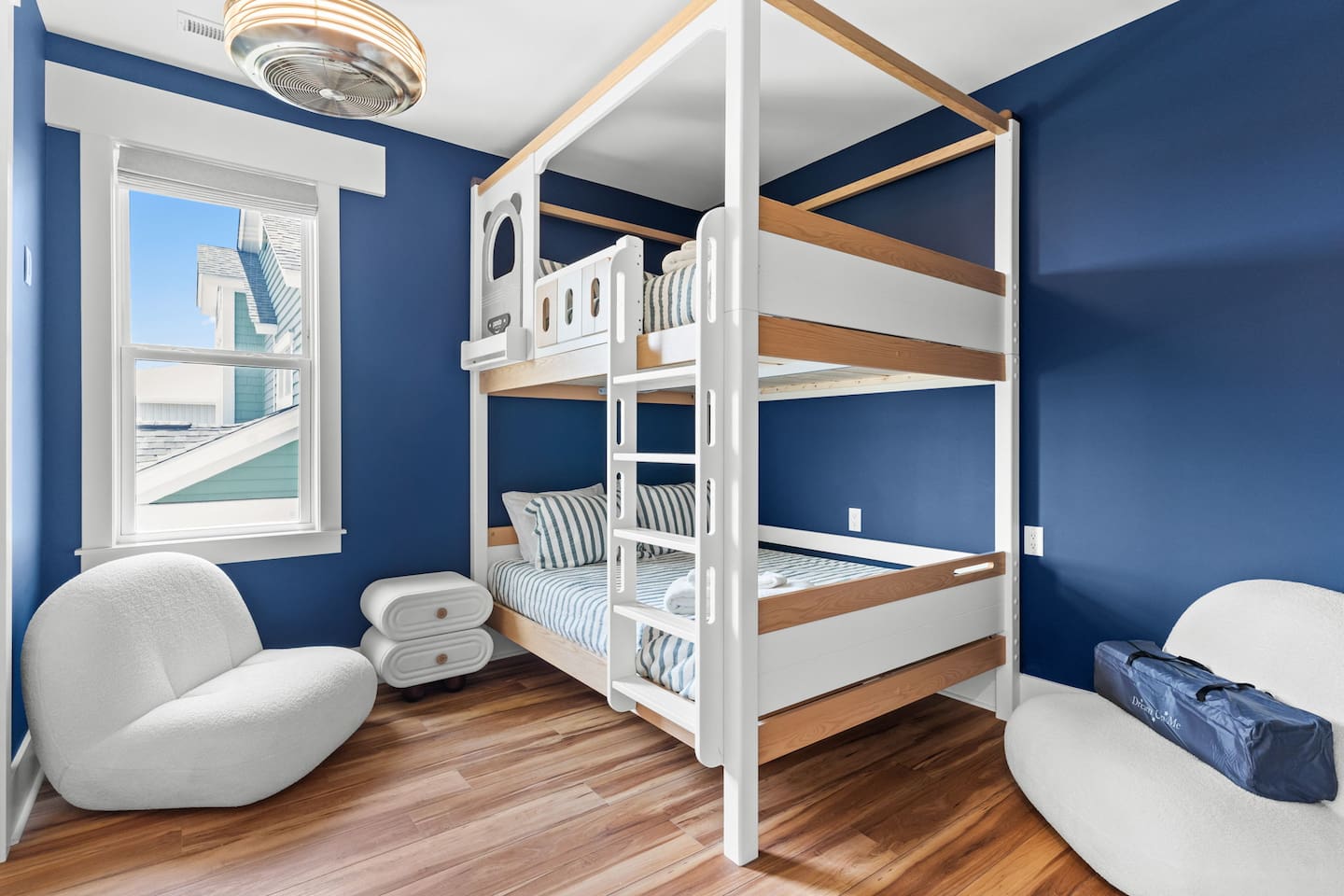 The upstairs bunk room includes a Queen-Over-Queen bunk bed with private en-suite bathroom (tub/shower) & 55-inch smart TV. Child-sized seating adds to the charm.
