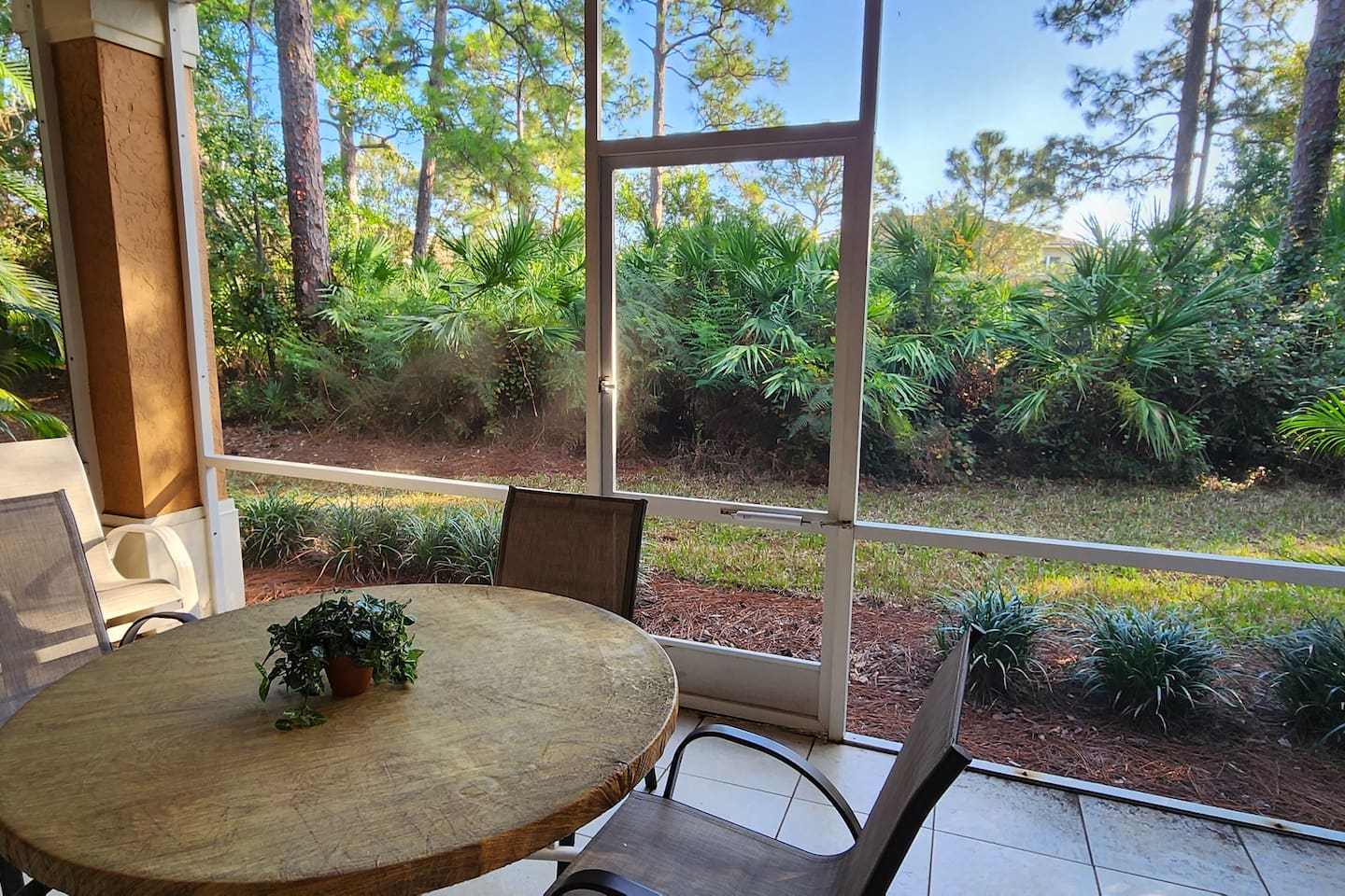 Private screened patio with outdoor seating and peaceful views of the surrounding landscaping.