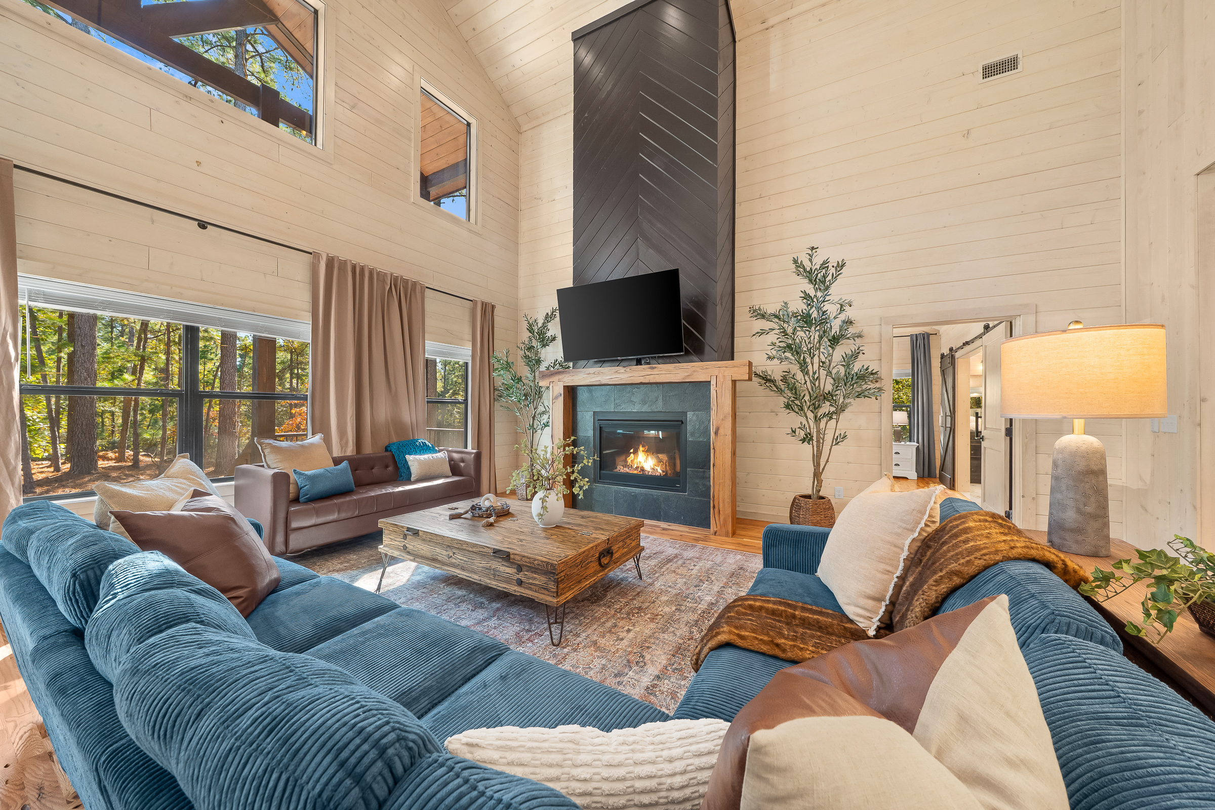A living room designed for connection. Floor to ceiling windows, a dramatic fireplace, and cozy textures bring everyone together.