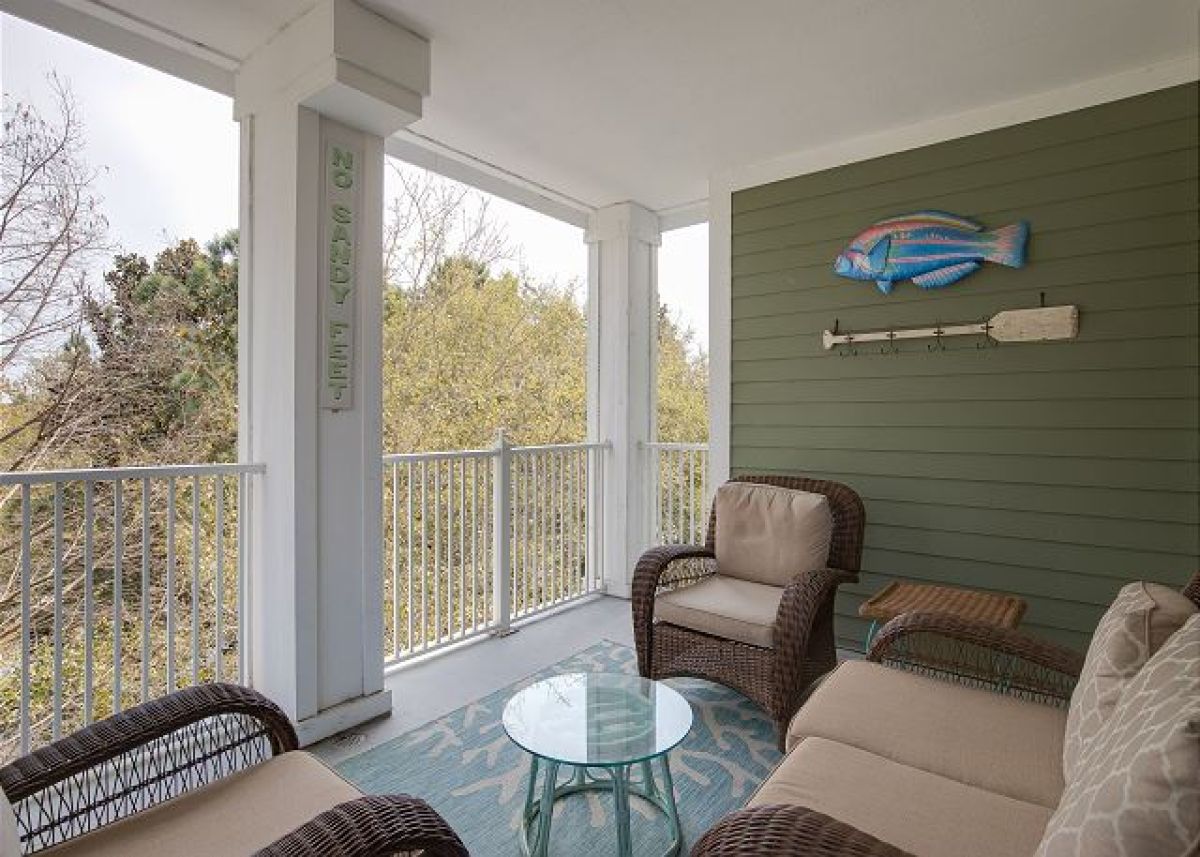 Balcony seating area with wicker furniture and coastal wall art on the fourth floor