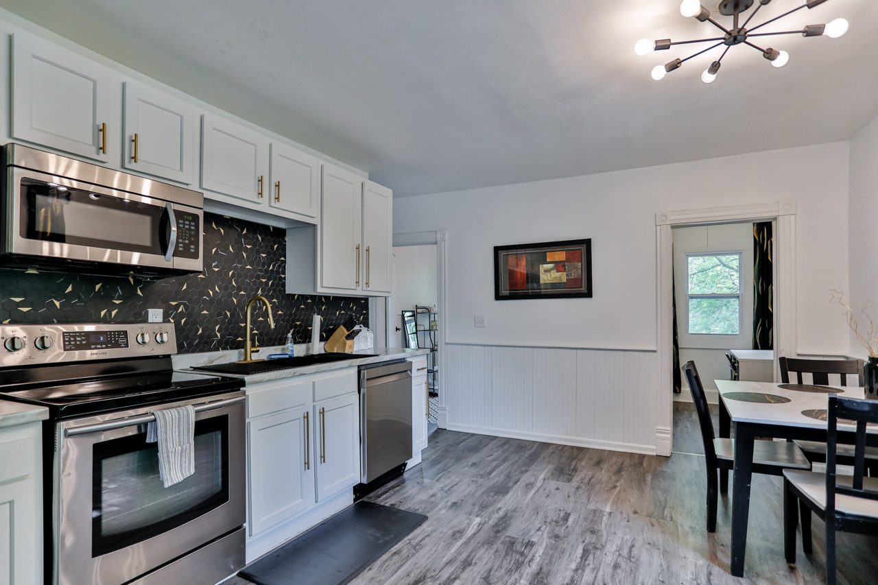 A modern kitchen equipped with high-end appliances and ample lighting. It has a coffee maker, oven, stove top, utensils, and all it takes to fix a delicious meal.