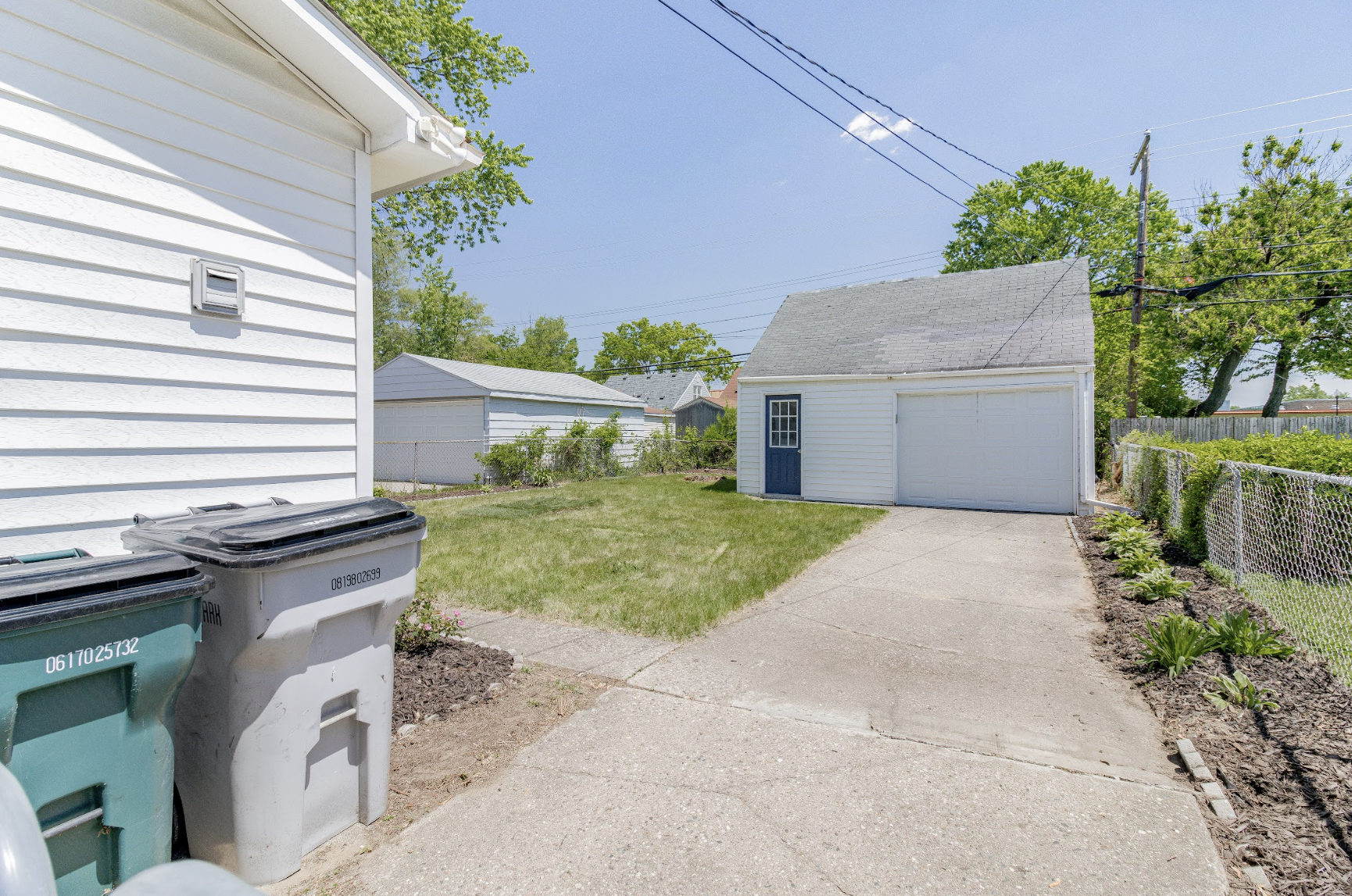 Spacious backyard with a detached garage, long driveway, and plenty of green space—perfect for parking and outdoor activities.