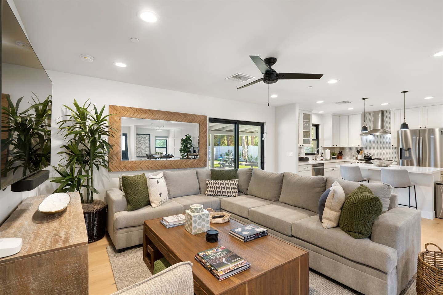 Relax in style in the living room, showcasing a plush sectional couch, a TV with a soundbar, and a ceiling fan to keep the atmosphere comfortable.