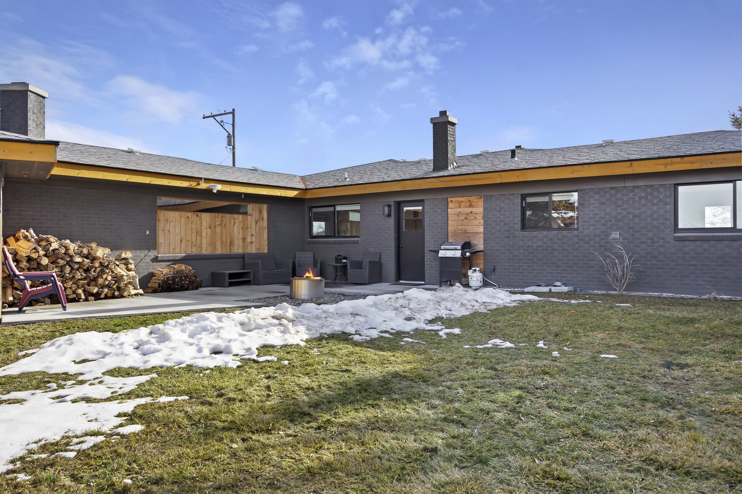 Backyard patio with fire pit, BBQ, and firewood — ready for a cozy winter stay