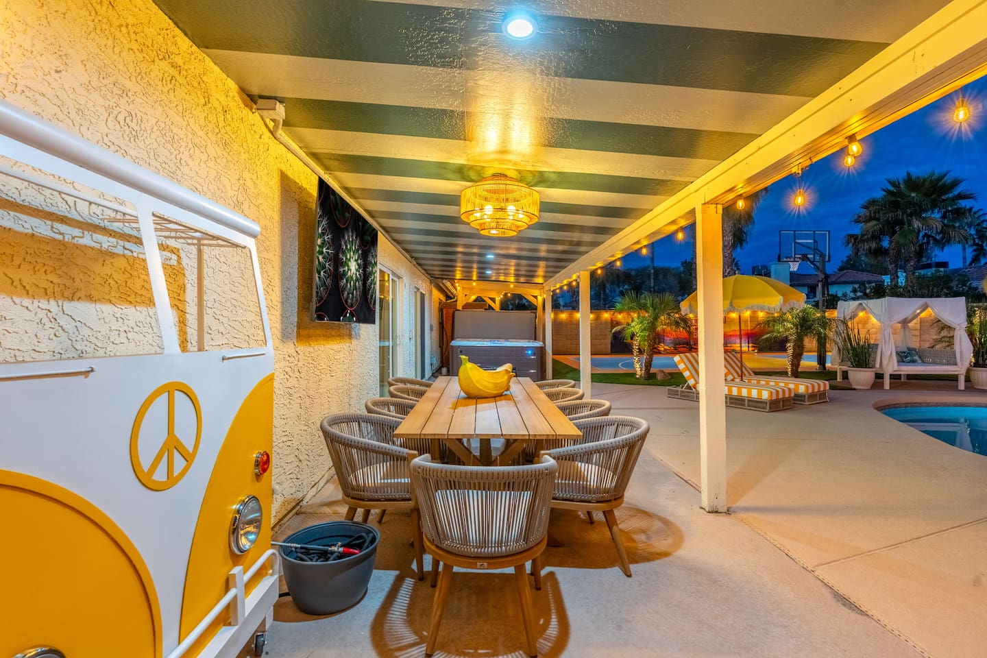 Covered patio with dining table, rattan chairs, and ambient lighting—ideal for evening gatherings and poolside entertaining.