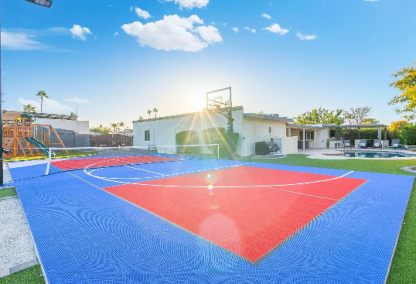 Sunlight streams across the court in this golden-hour shot, framed by the home and mountains beyond.