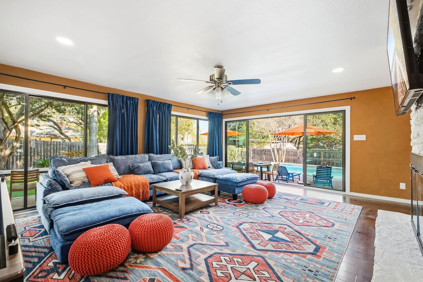 Living room with large TV, comfortable seating, and backyard views