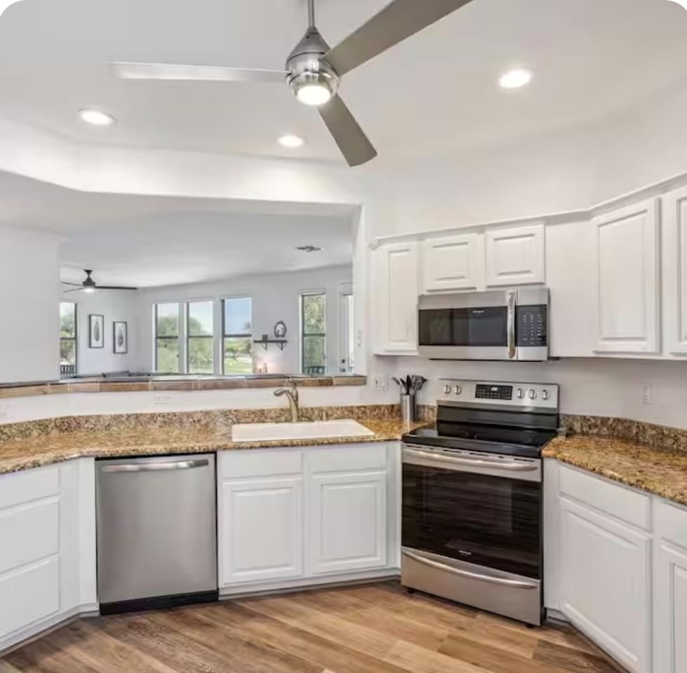Kitchen with stainless steel appliances, dishwasher, granite counters, and open views into the living area.