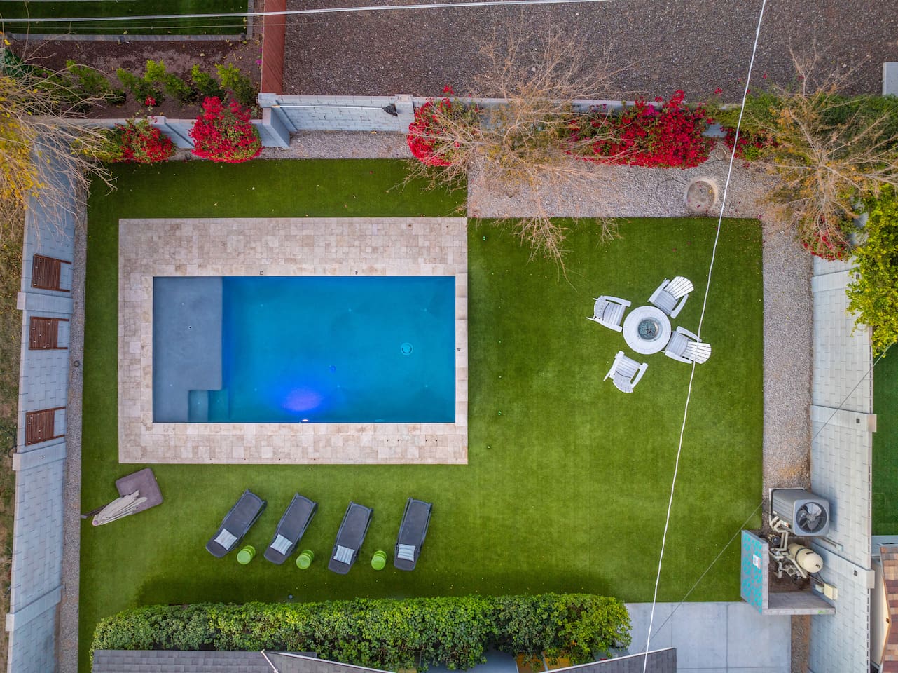 Aerial view of the backyard, capturing the expansive layout with the pool, seating areas, and surrounding greenery for a complete perspective.