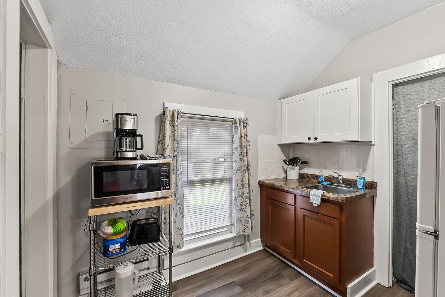 A compact kitchenette with everything you need — microwave, coffee maker, and full-size fridge tucked neatly into the space.