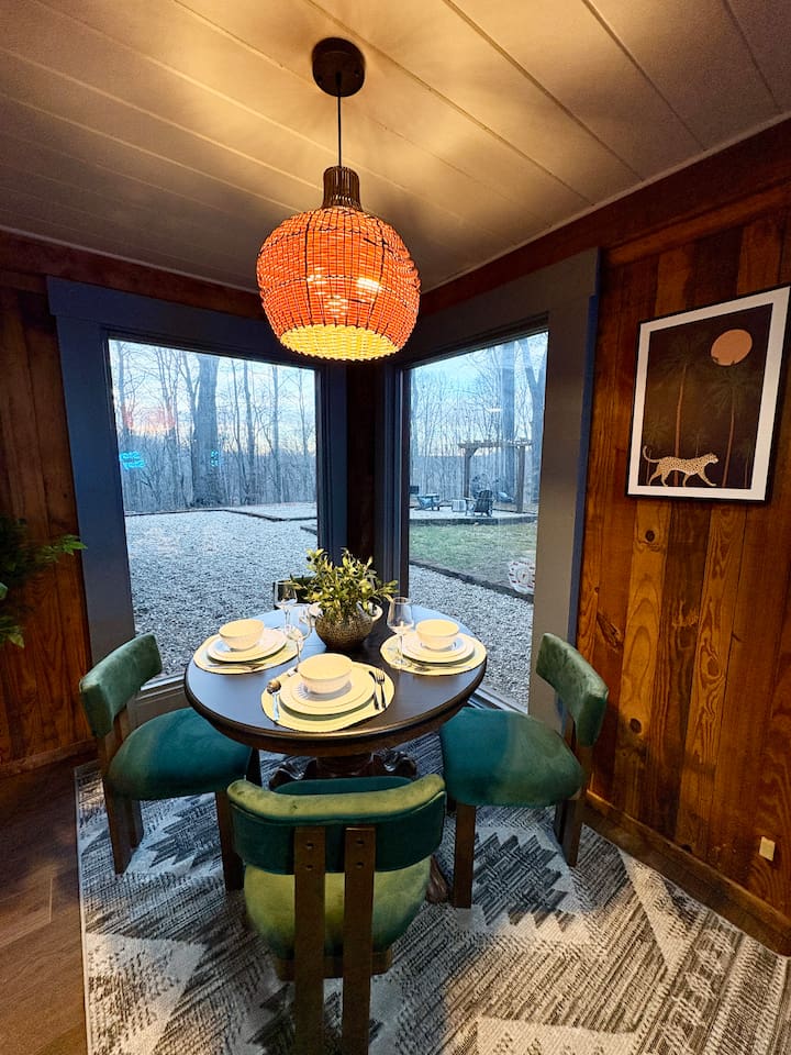 Dining table set against rich wood paneling and vibrant greenery.
