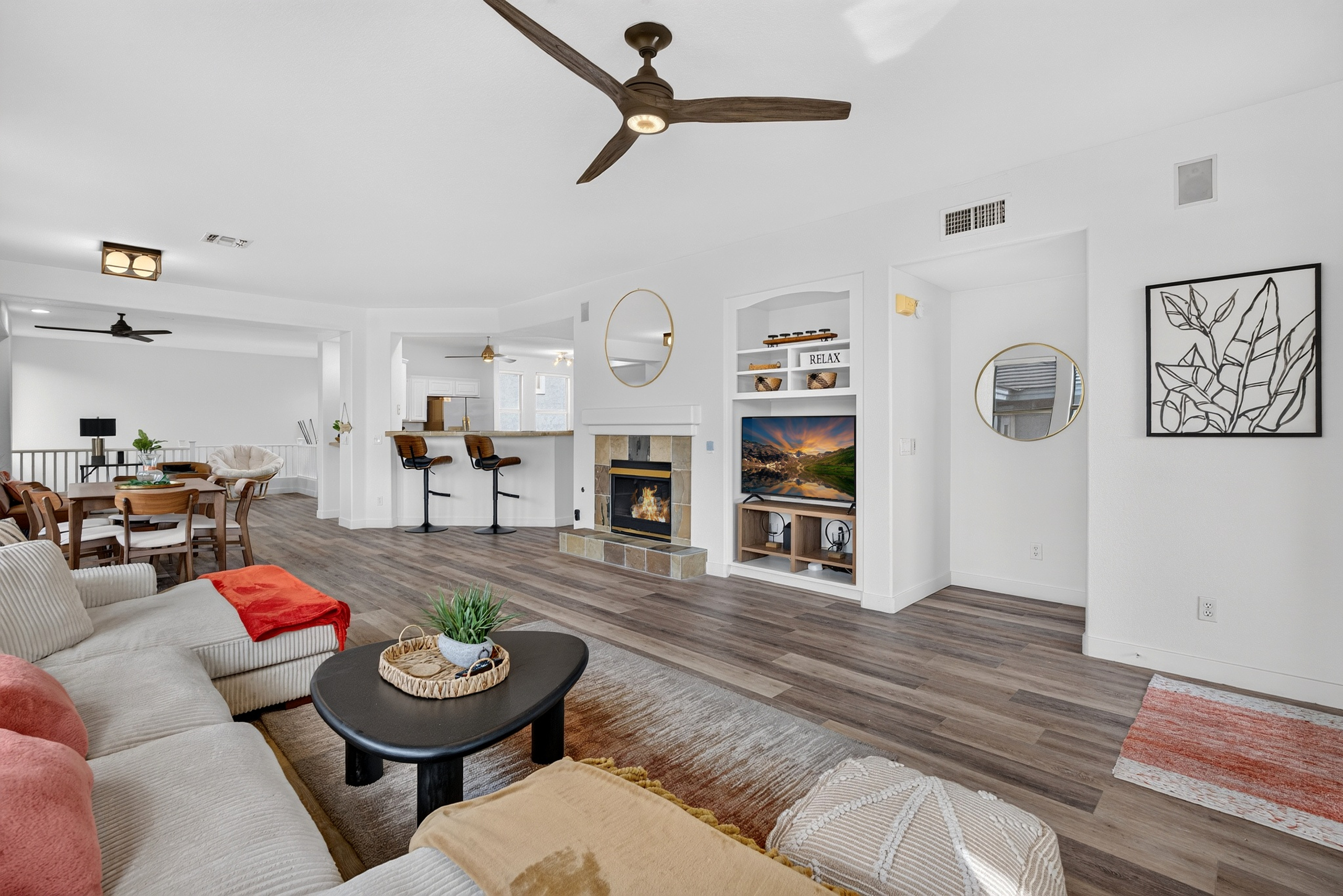 Open living area with comfortable sectional seating, TV, fireplace, and easy flow to the dining and kitchen spaces.