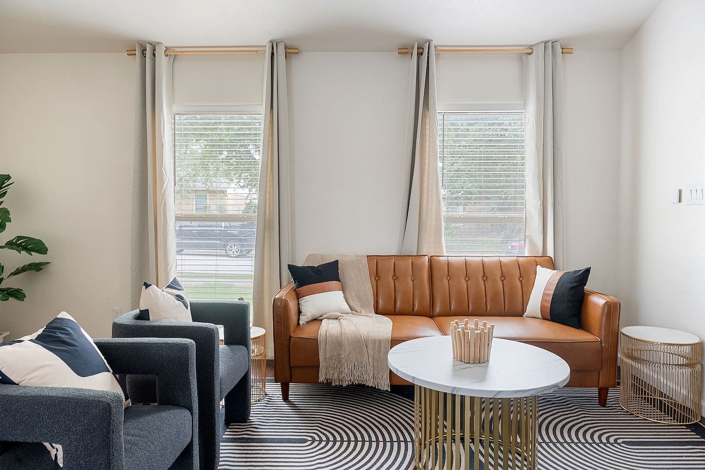 Settle into this comfortable living space featuring a chic sofa and modern armchairs. Large windows allow plenty of natural light, enhancing the decor.