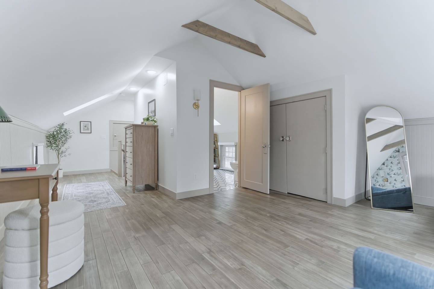 Spacious loft layout with open floor space, dresser storage, full-length mirror, and easy access to the bathroom.