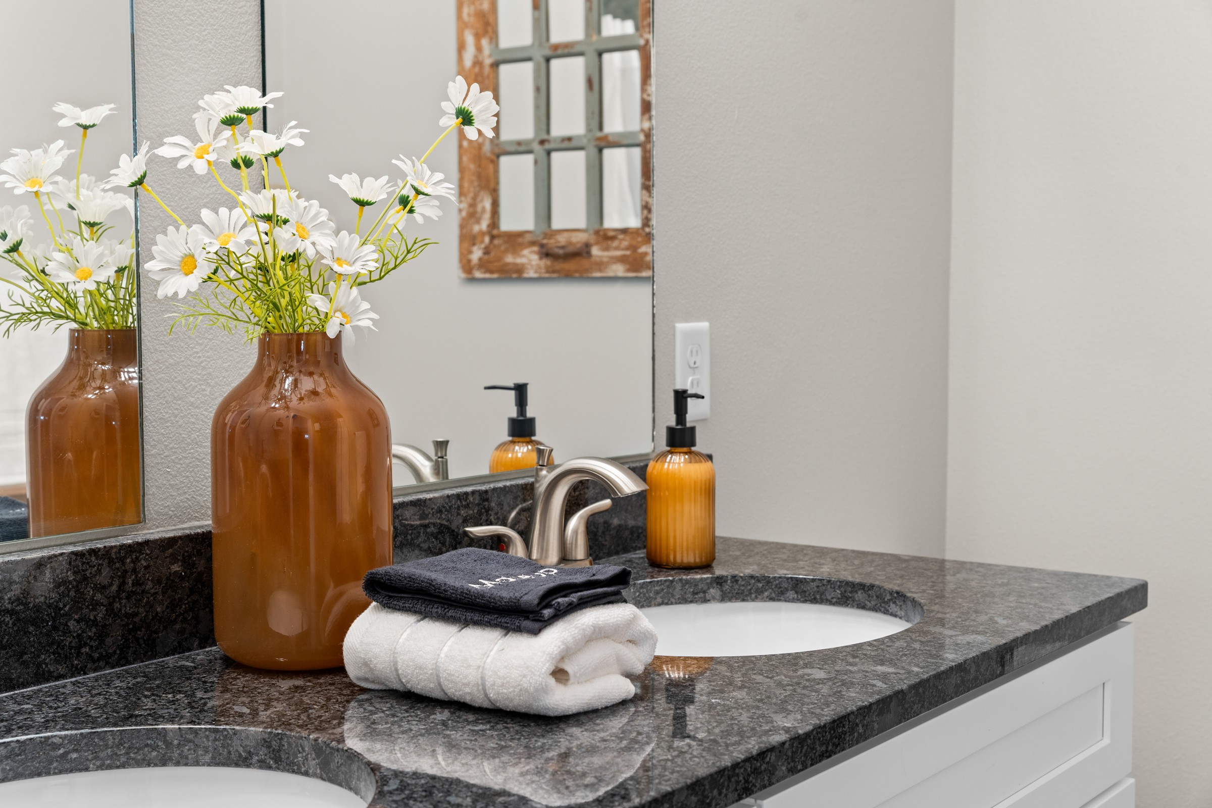 Double-vanity counter with fresh daisies, soap, and folded towels. Small touches that make you know you're looked after.