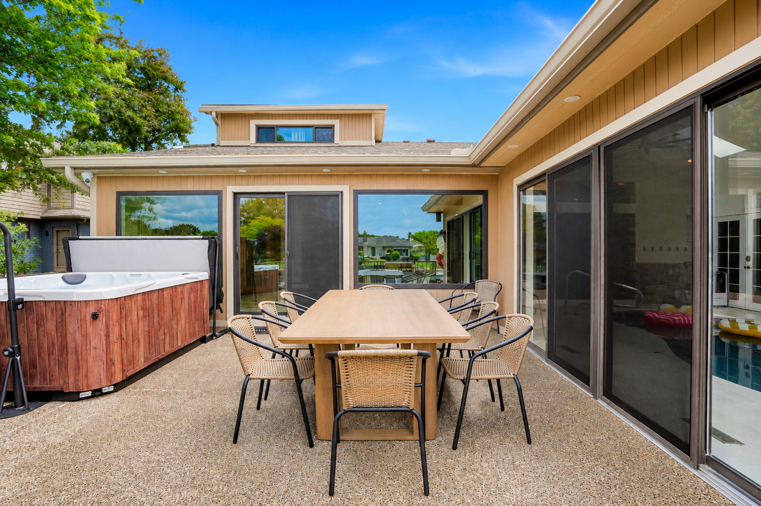 Spacious outdoor patio with dining table, seating, and a private hot tub. Perfect for relaxing, entertaining, and enjoying warm-weather lake house living.
