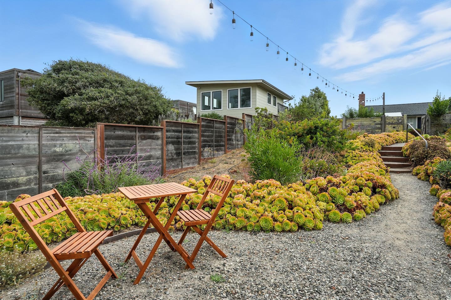 - Charming garden seating area with bistro table and string lights overhead  
- Surrounded by beautiful greenery and colorful plants for a peaceful setting  
- Perfect spot for morning coffee, reading, or intimate evening chats  
