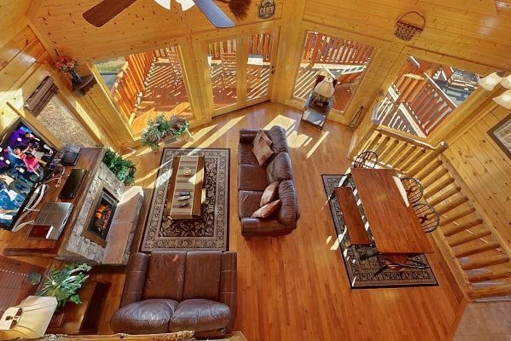 - Overhead view reveals a stunning open-concept living and dining space   - Floor-to-ceiling windows fill the cabin with mountain light and scenic views   - Warm log interiors create the ultimate Smoky Mountain getaway atmosphere