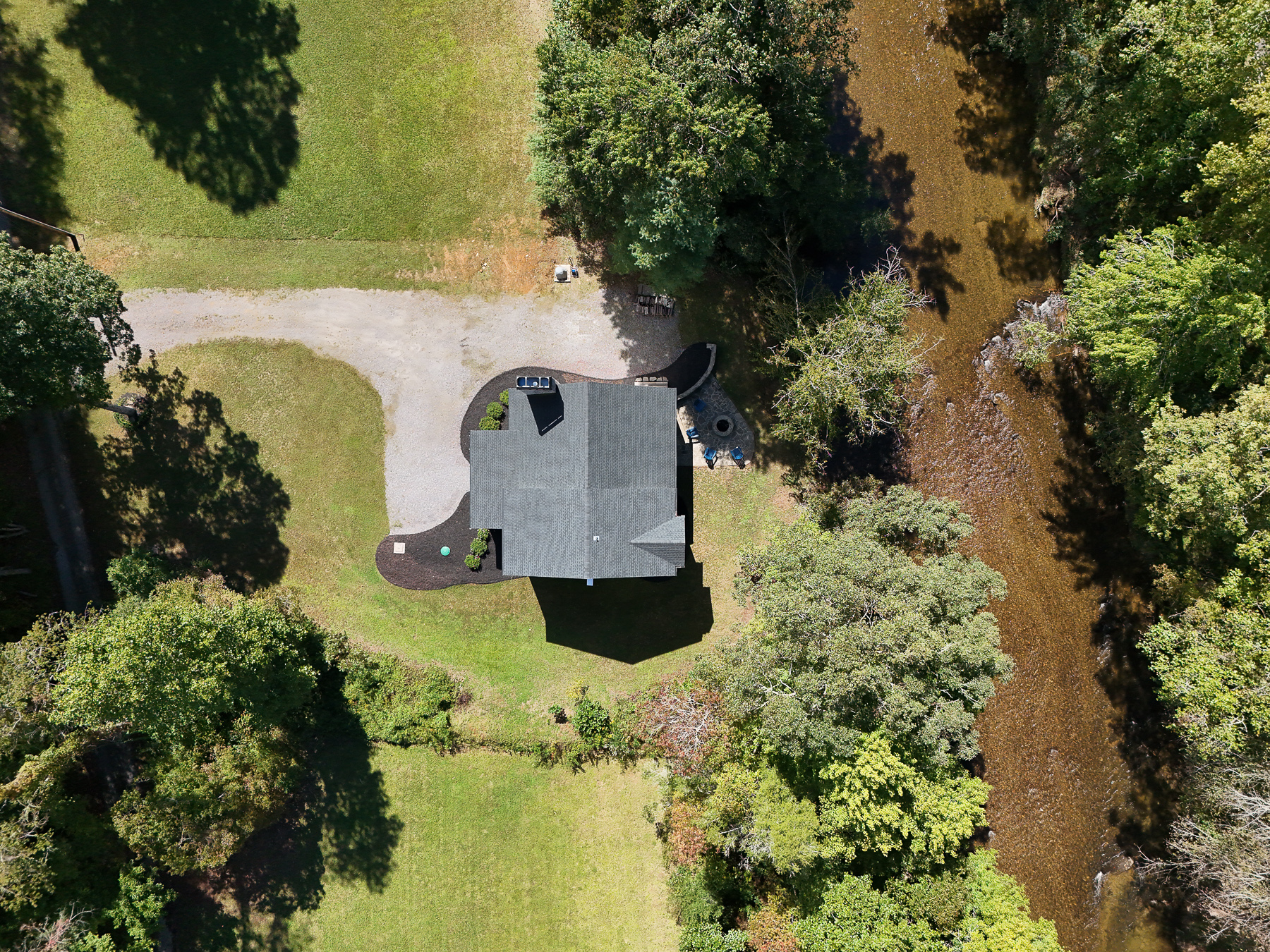 An overhead view of Robbin’s Nest on Snowbird Creek highlights the grassy yard, gravel driveway, and fire pit just steps from the creek.