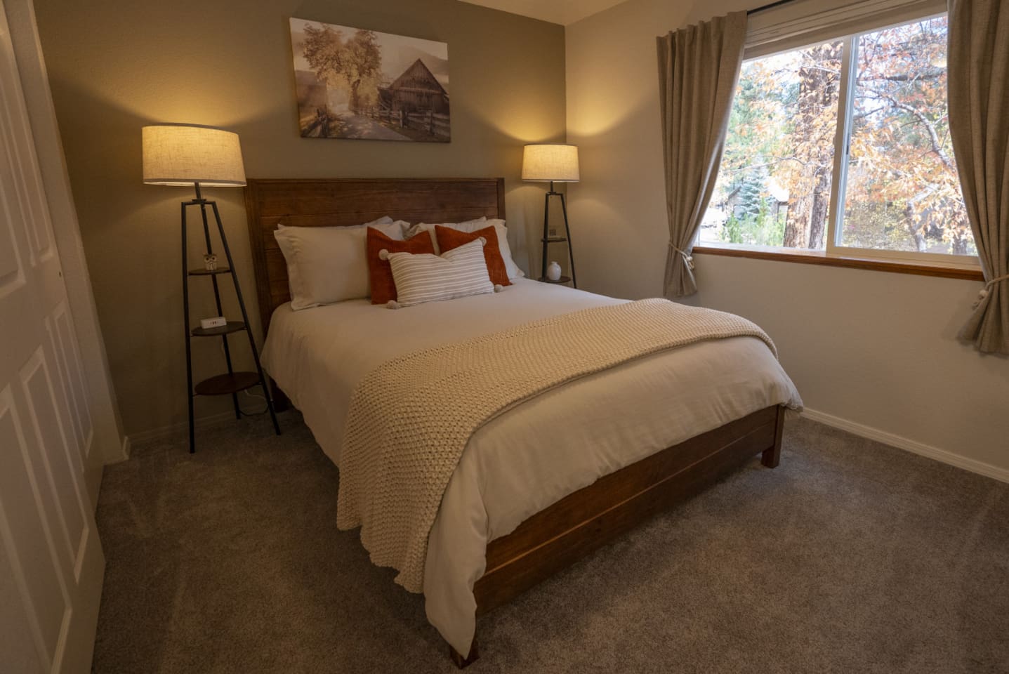 Queen bedroom with soft bedding, bedside lighting, closet storage, and a bright window view.