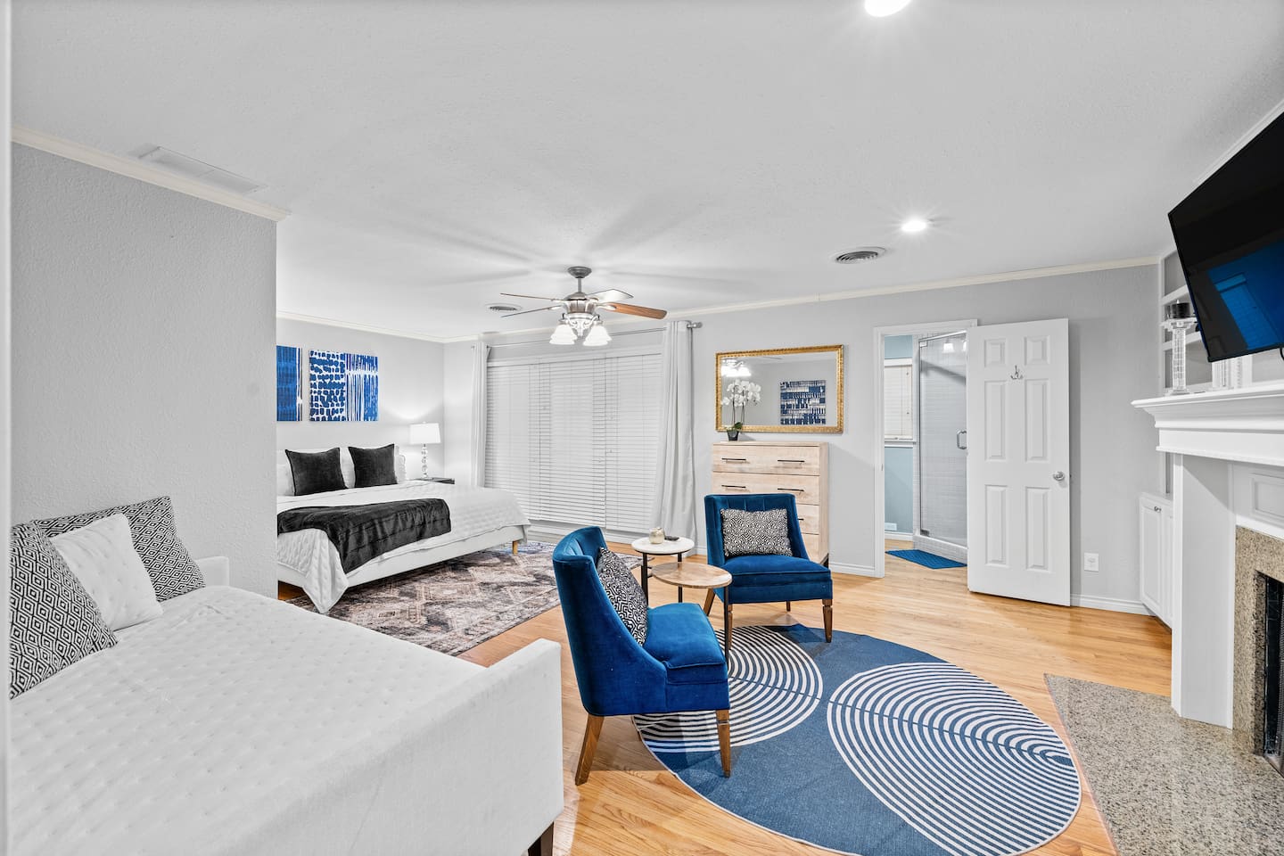 Relax in the spacious primary suite featuring bold blue accent chairs, a king bed, and a cozy daybed—all in one stylish retreat.